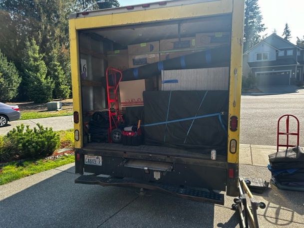 Yellow moving truck open, packed with furniture and boxes, parked on a residential street.