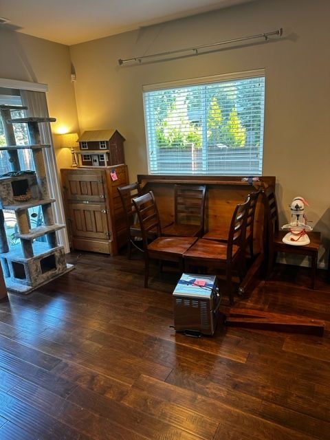 Wooden furniture inside a room with hardwood floors. Includes a cat tree, window, chairs, and cabinets.