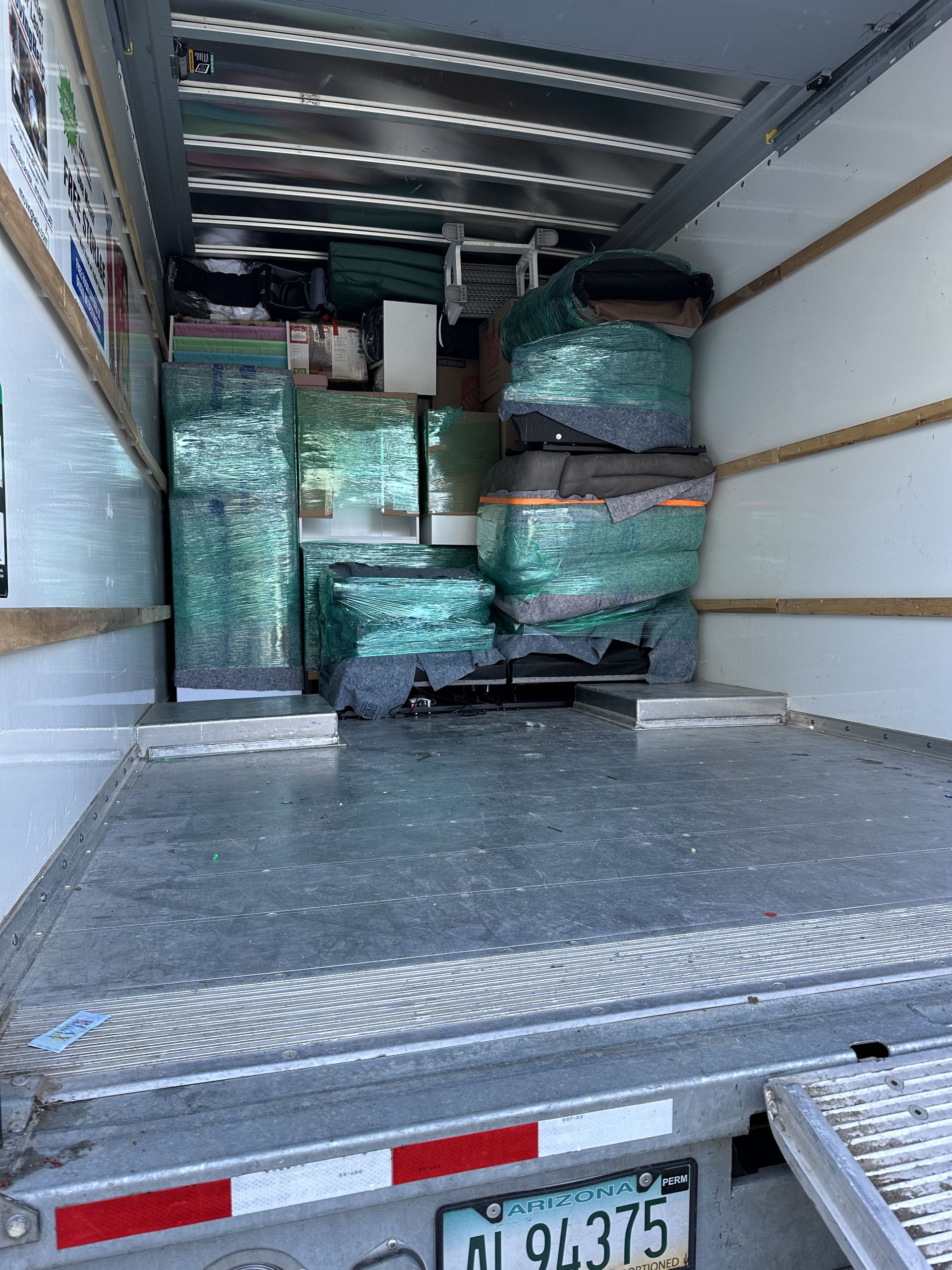 Interior of a moving truck filled with wrapped furniture and boxes.