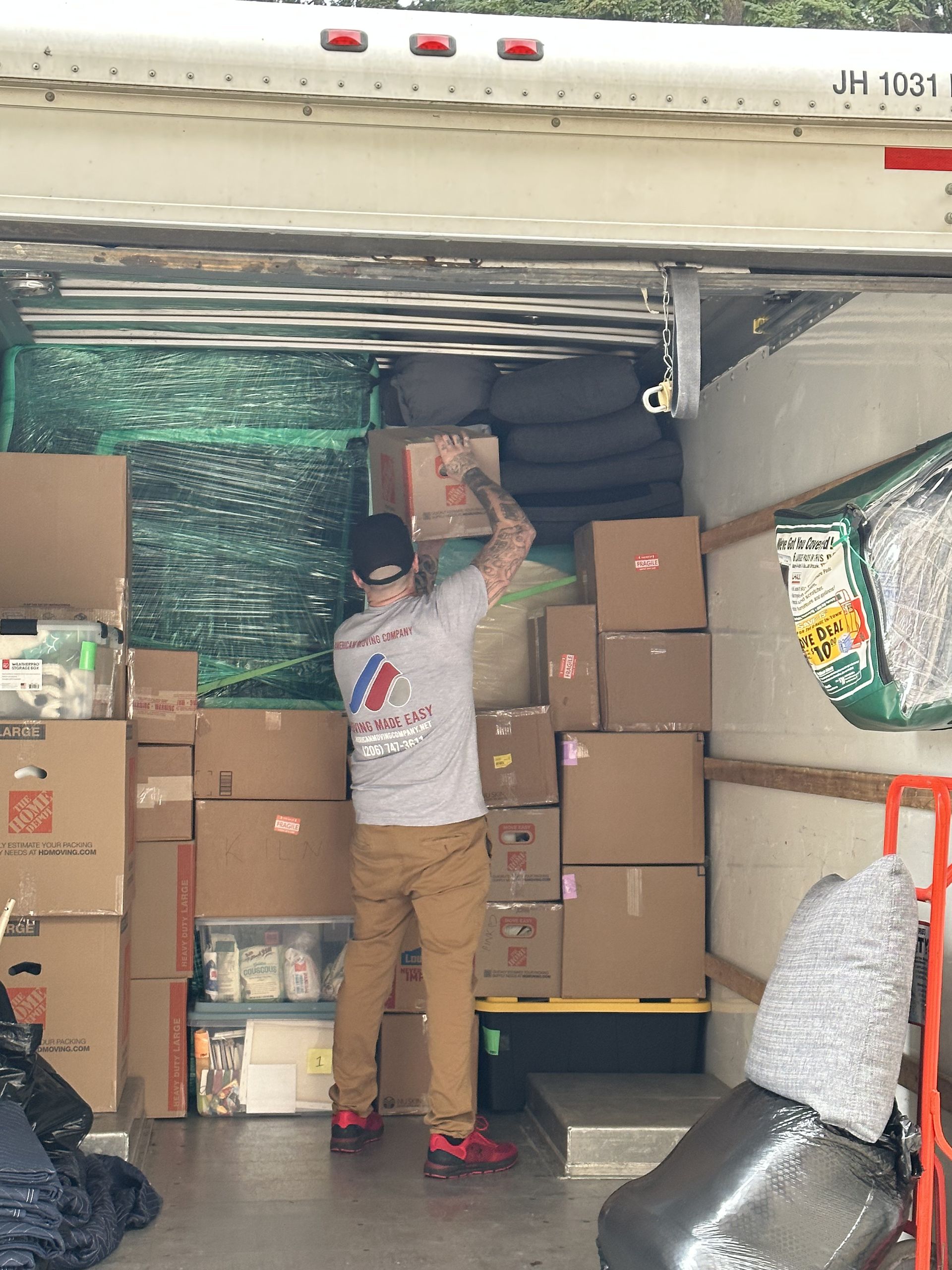 Man loading boxes into a moving truck. Interior view with stacked boxes, a ramp, and protective materials.