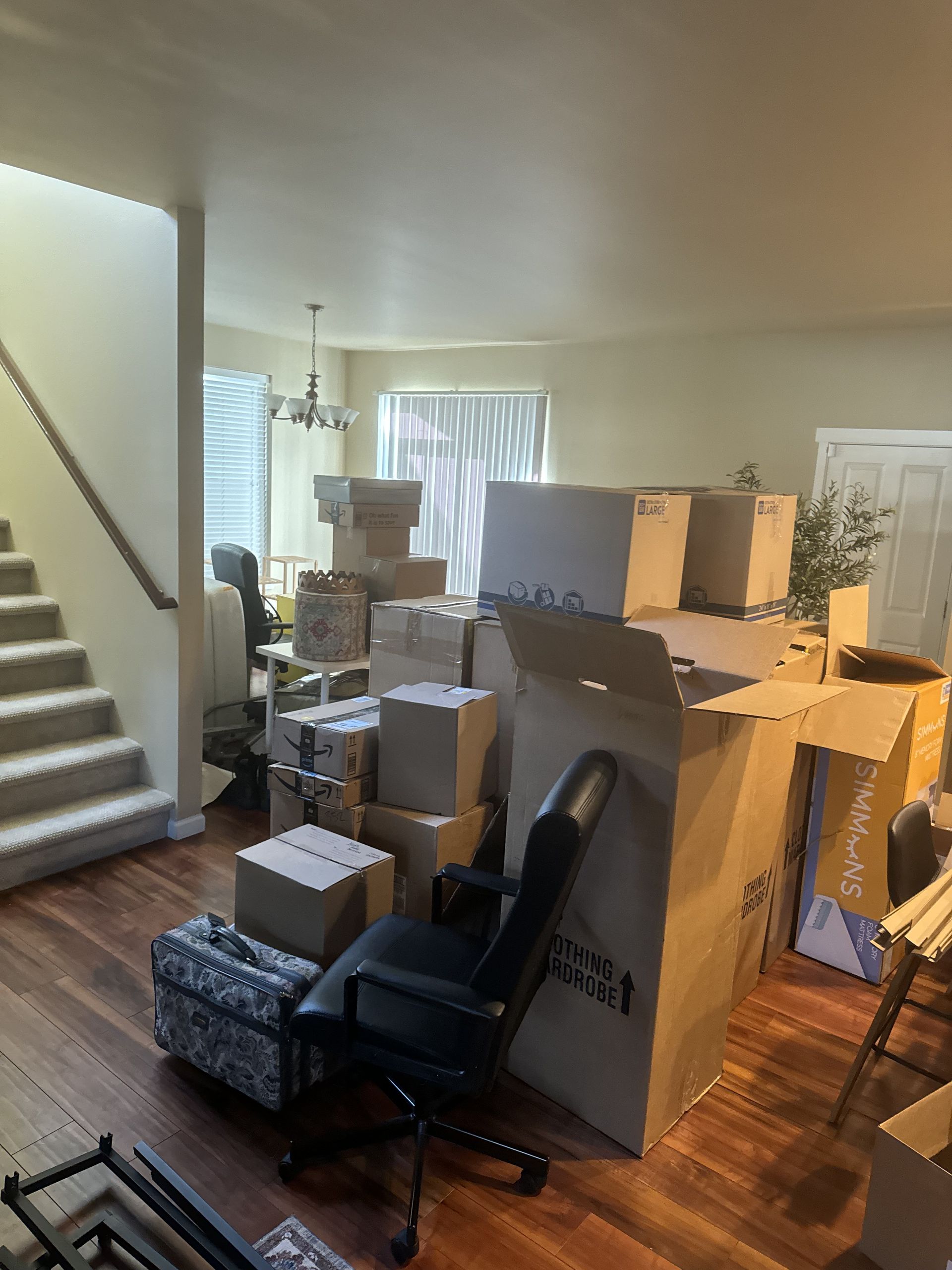 Living room filled with moving boxes. Boxes are stacked on top of each other and around a desk chair.