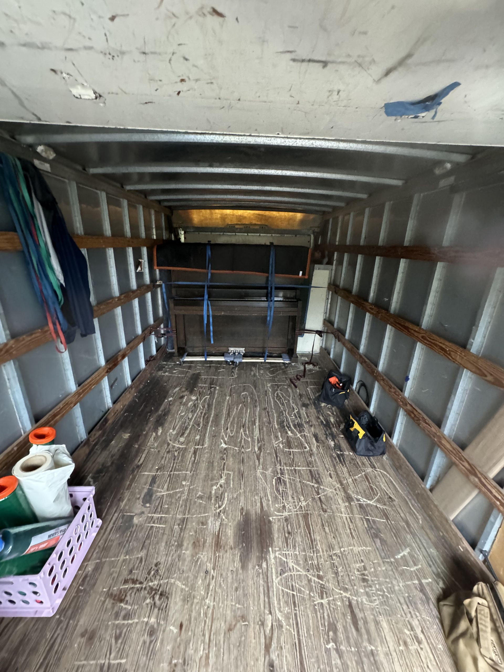Inside of a truck cargo area with wooden floor and metal beams, various items are placed throughout.