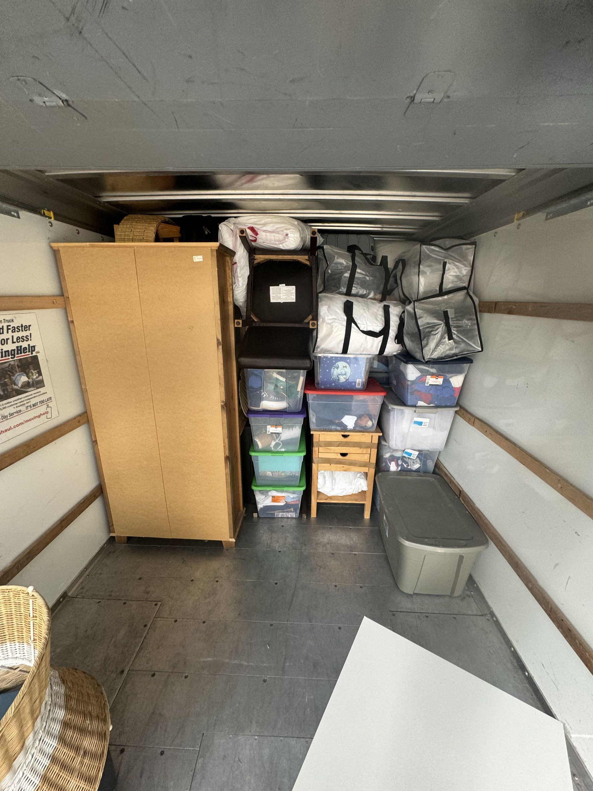 Interior of a moving truck packed with furniture, boxes, and storage bins.