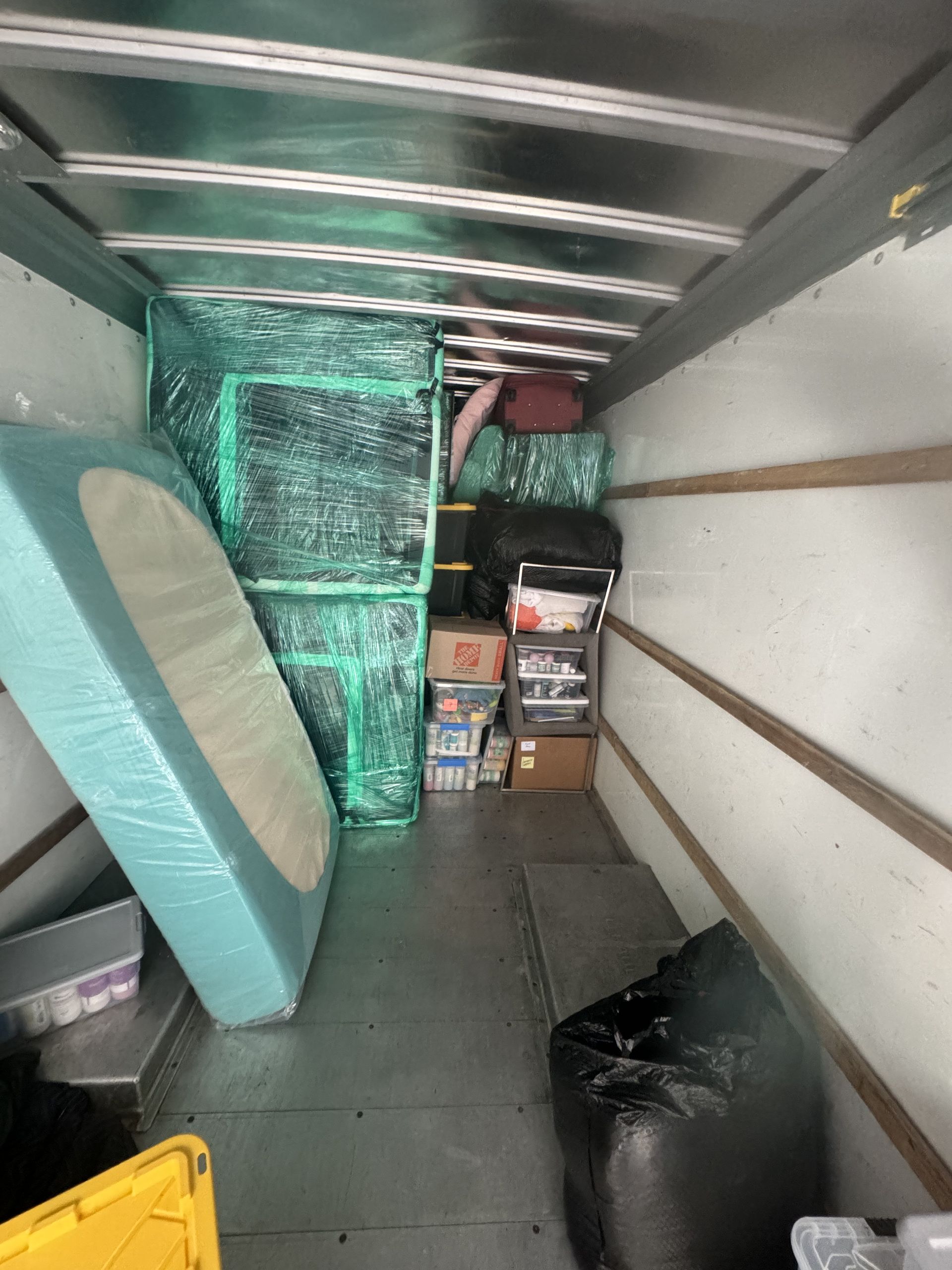 Interior of a moving truck packed with furniture, boxes, and a mattress, ready for transport.