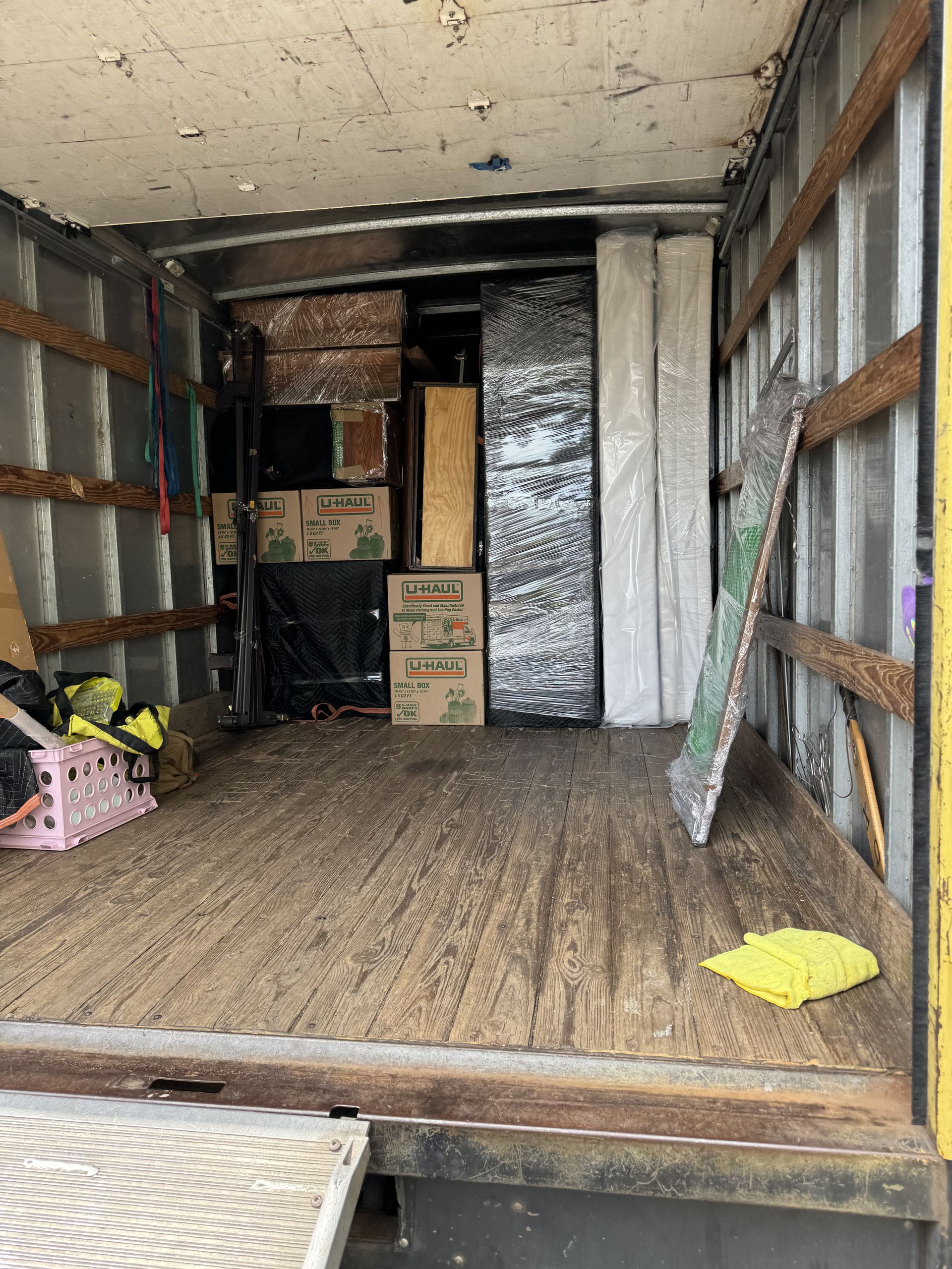 Interior of a moving truck with packed boxes, furniture, and a mattress, ready for transport.