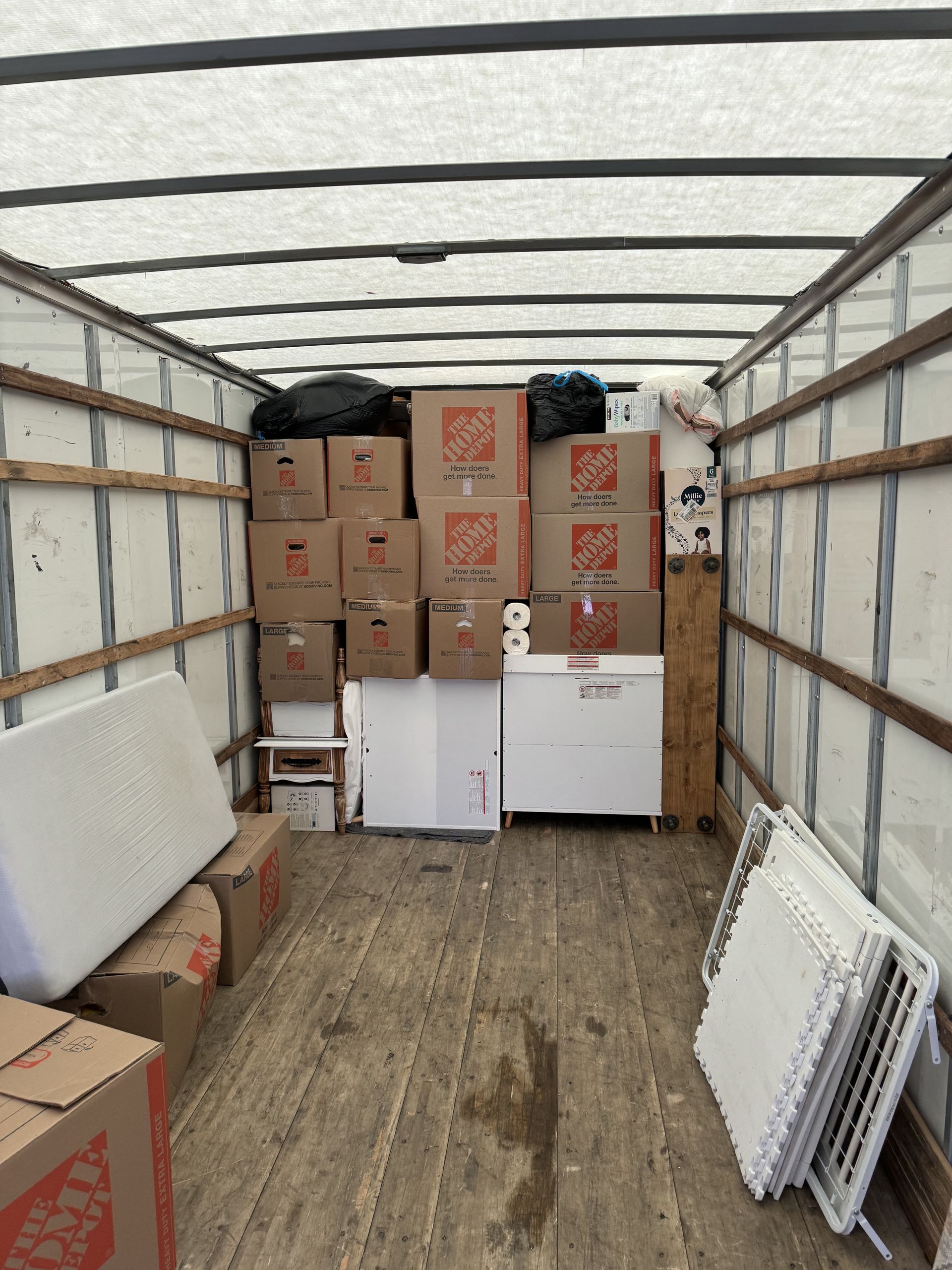 Inside of a moving truck filled with cardboard boxes, a chest freezer, and other items.
