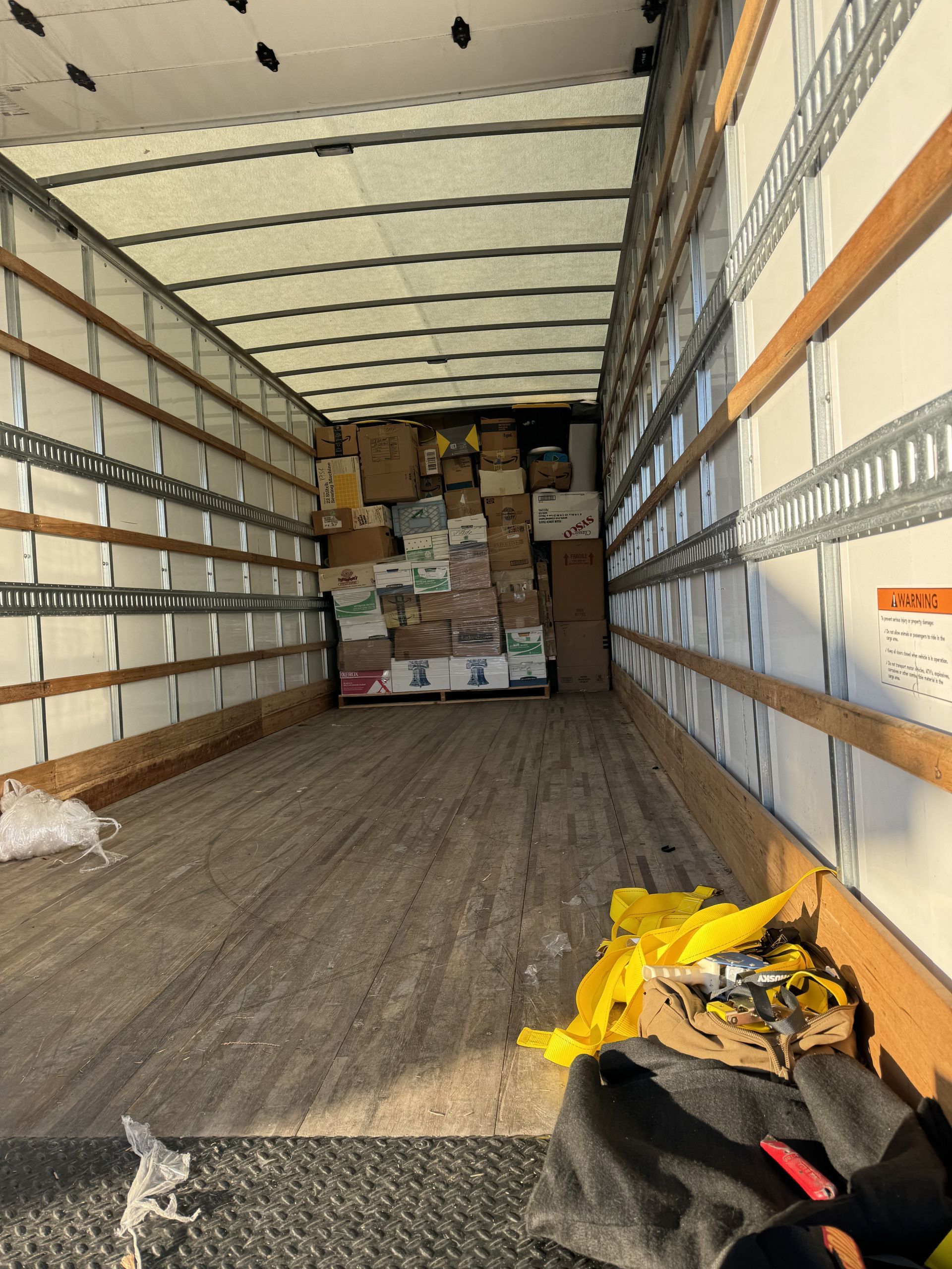 Interior of a cargo truck filled with boxes and items, partially blocking the view down the length of the truck.