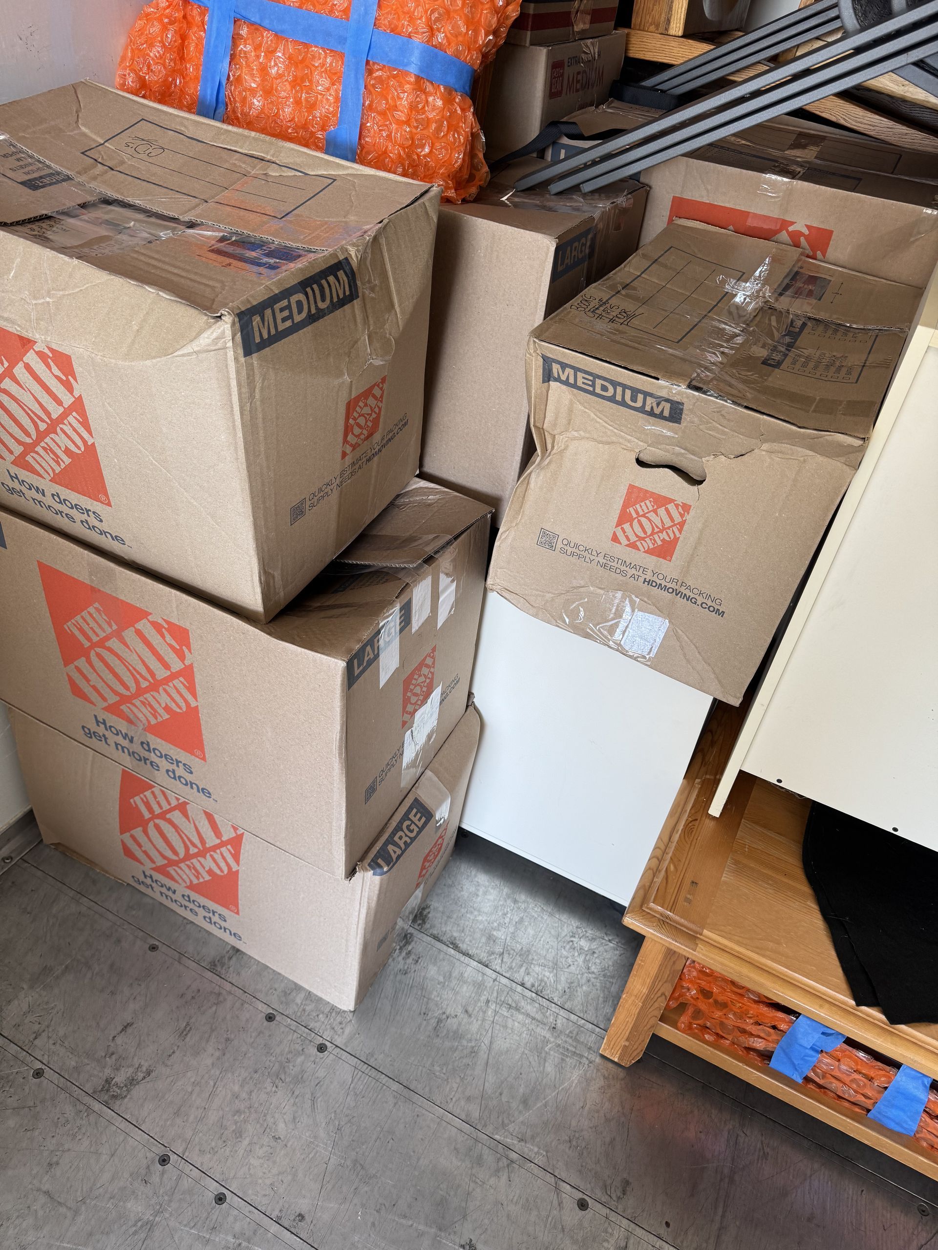 Boxes of various sizes stacked in a cluttered room, some with the Home Depot logo.