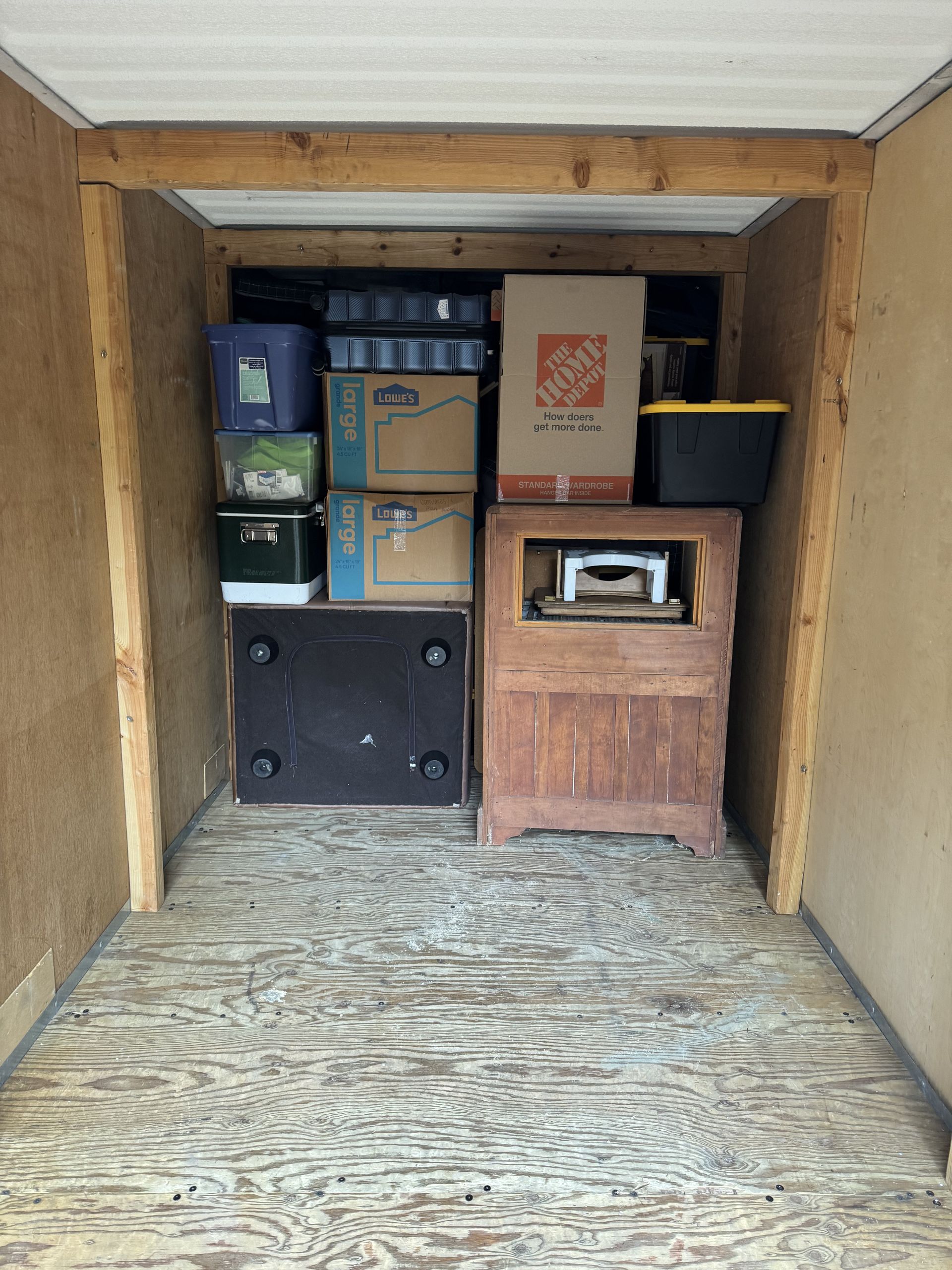 Interior of storage unit with boxes, wooden cabinet, and other items.