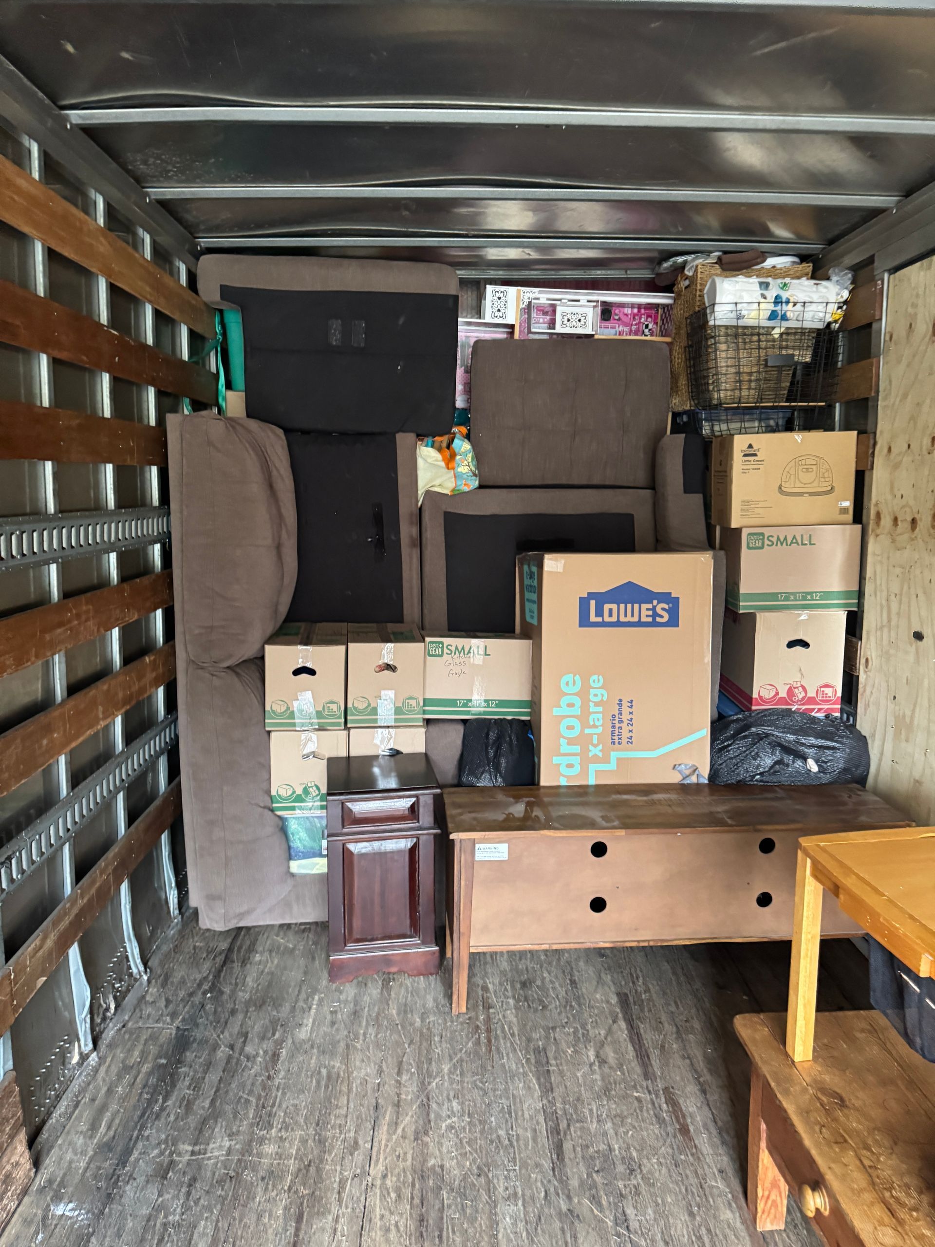 Interior of a moving truck packed with furniture and boxes, including a dresser and sofa pieces.
