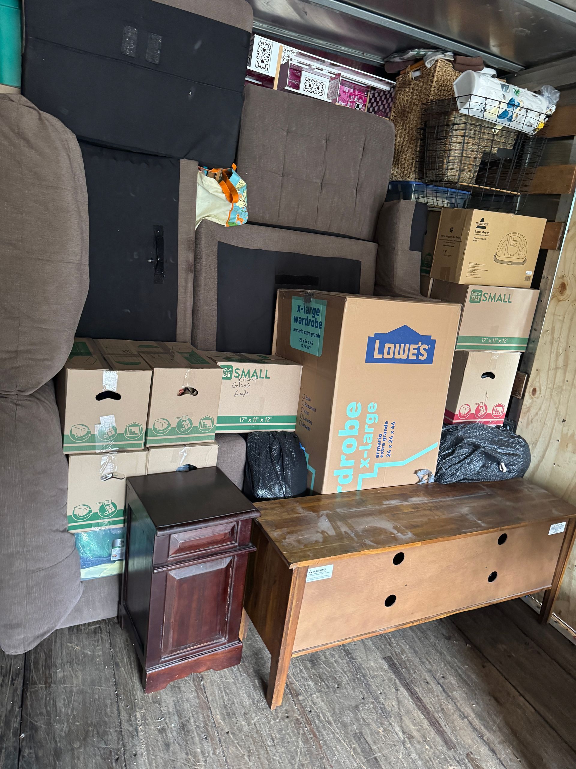 Interior of a moving truck packed with furniture, boxes, and baskets.