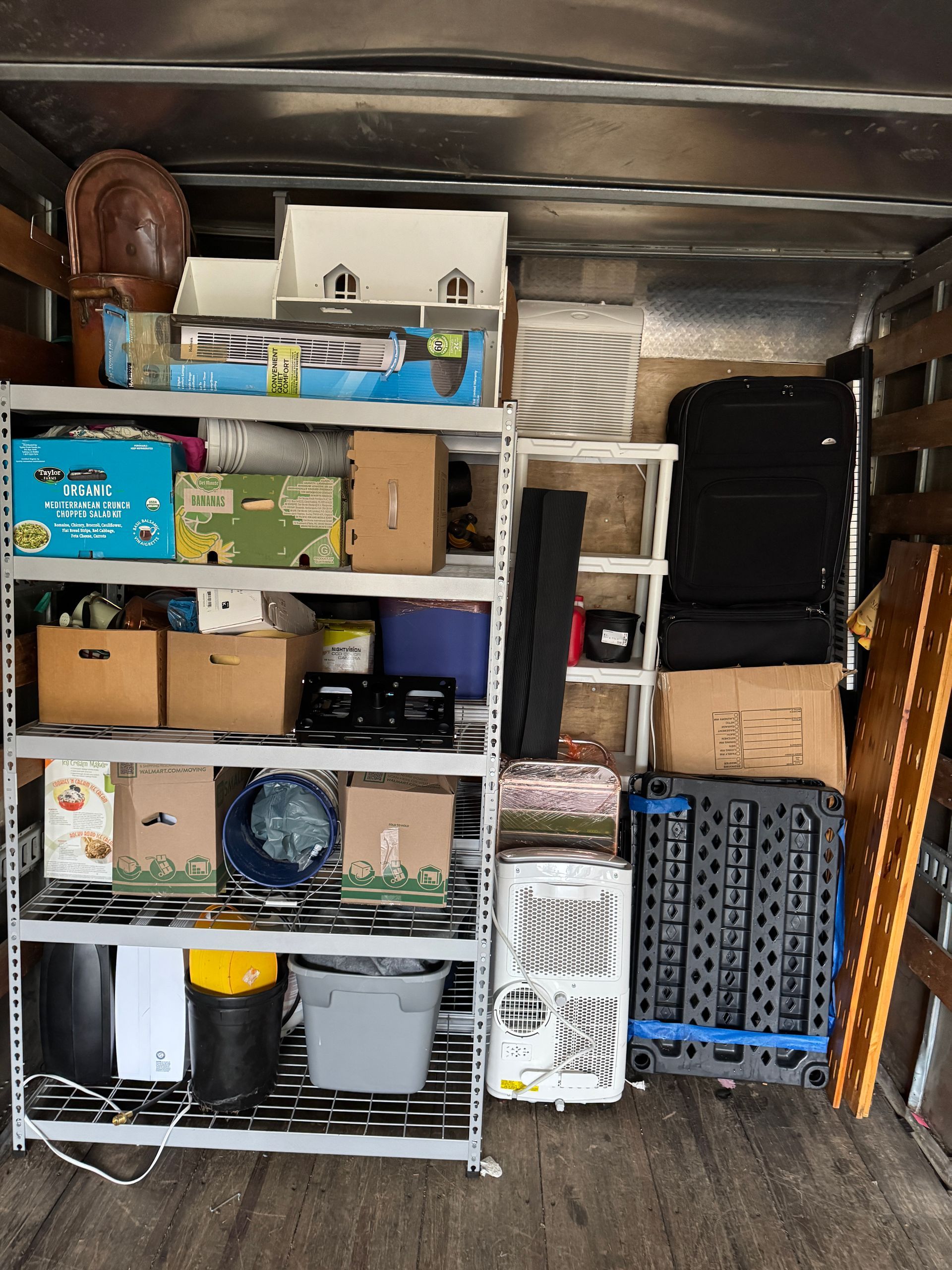 A truck cargo area filled with various boxes, items, and shelving units during a move.