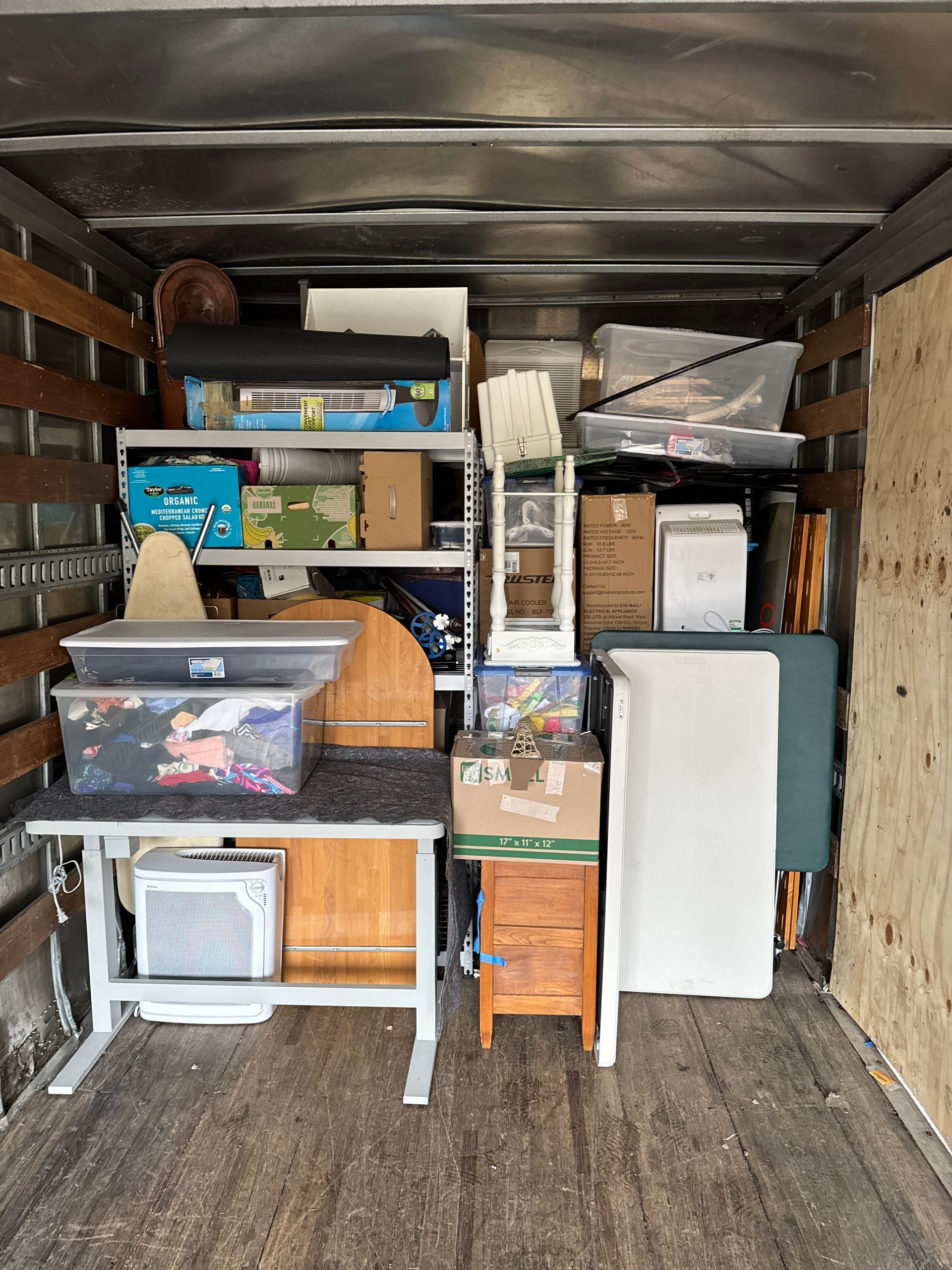Truck interior filled with packed boxes, furniture, and various household items during a move.