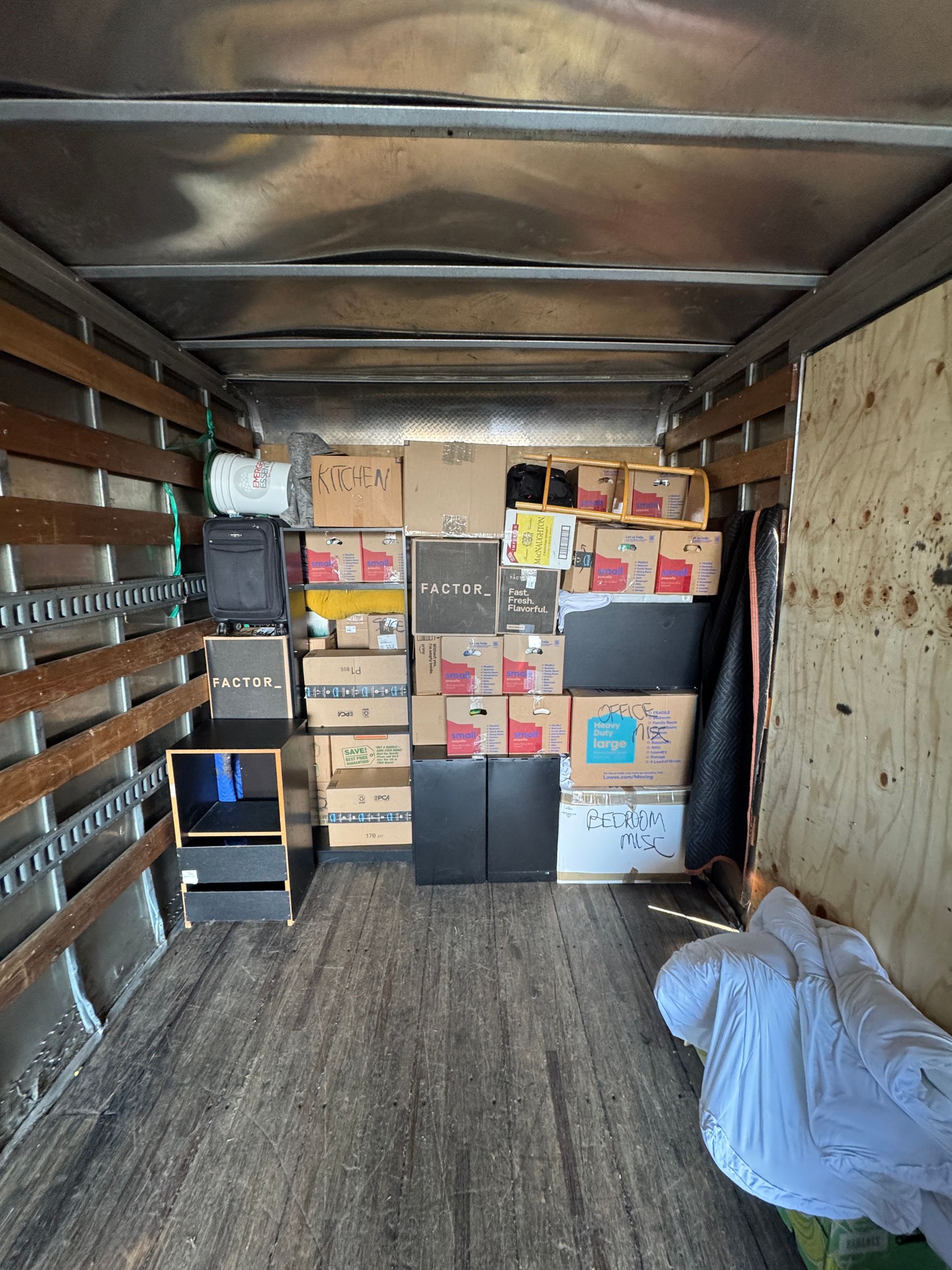 Interior of a moving truck filled with cardboard boxes, furniture, and belongings ready for transport.