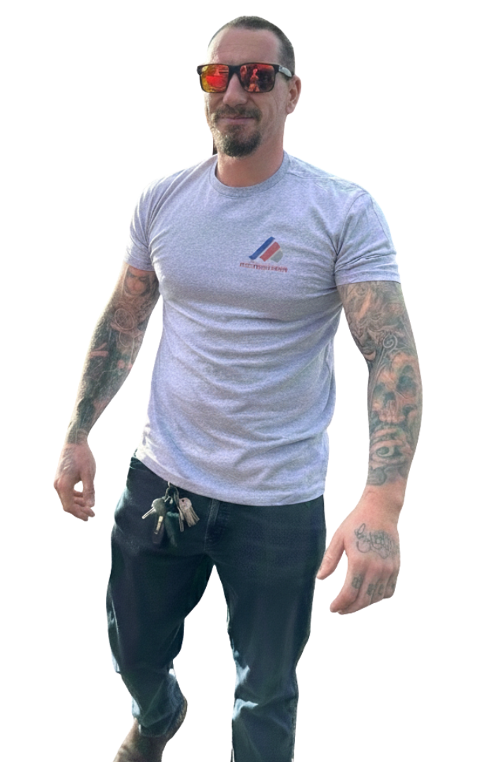 Man with tattoos wearing sunglasses, gray t-shirt, and jeans, holding keys.