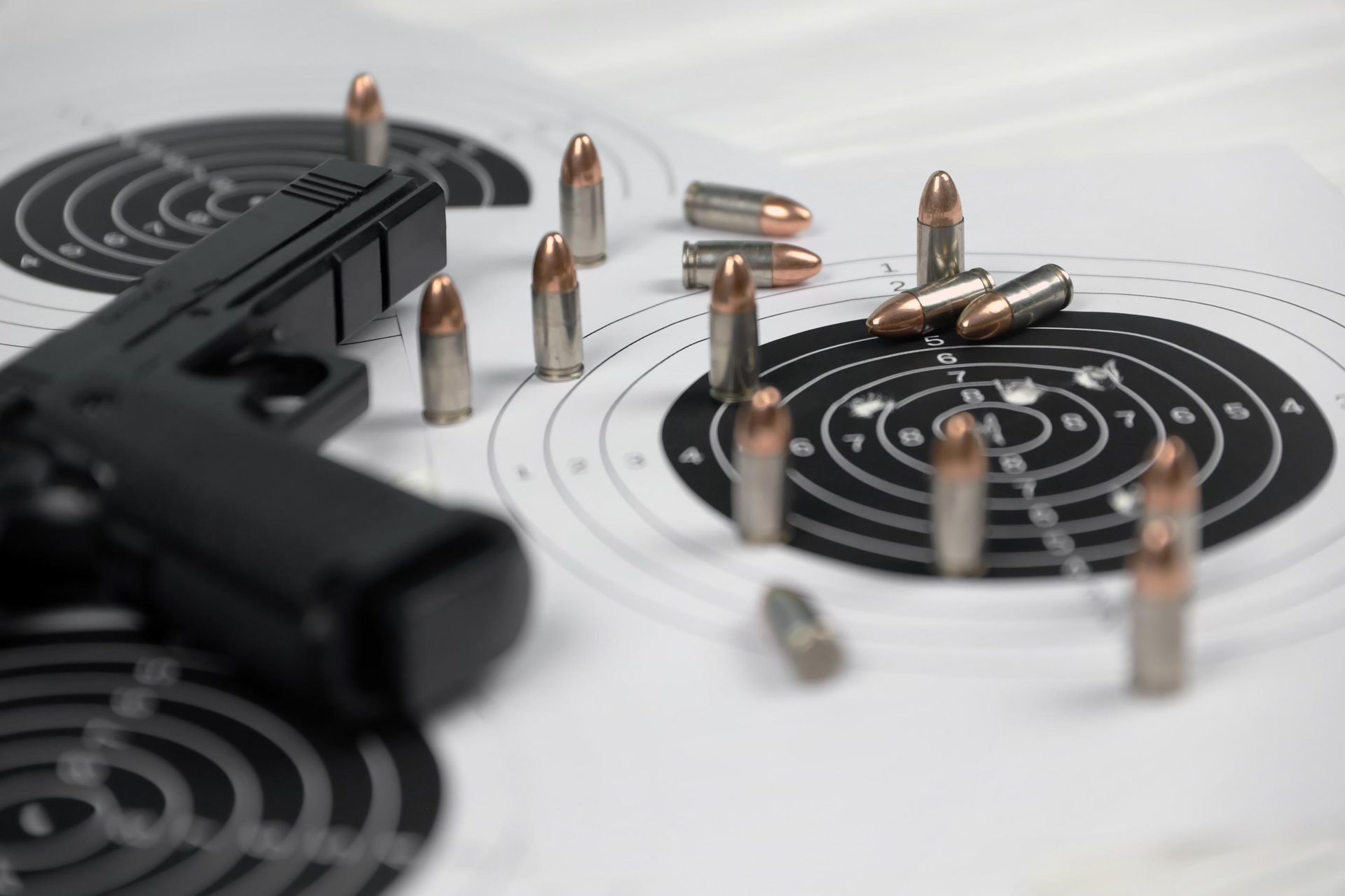 Black handgun and bullets on shooting targets.