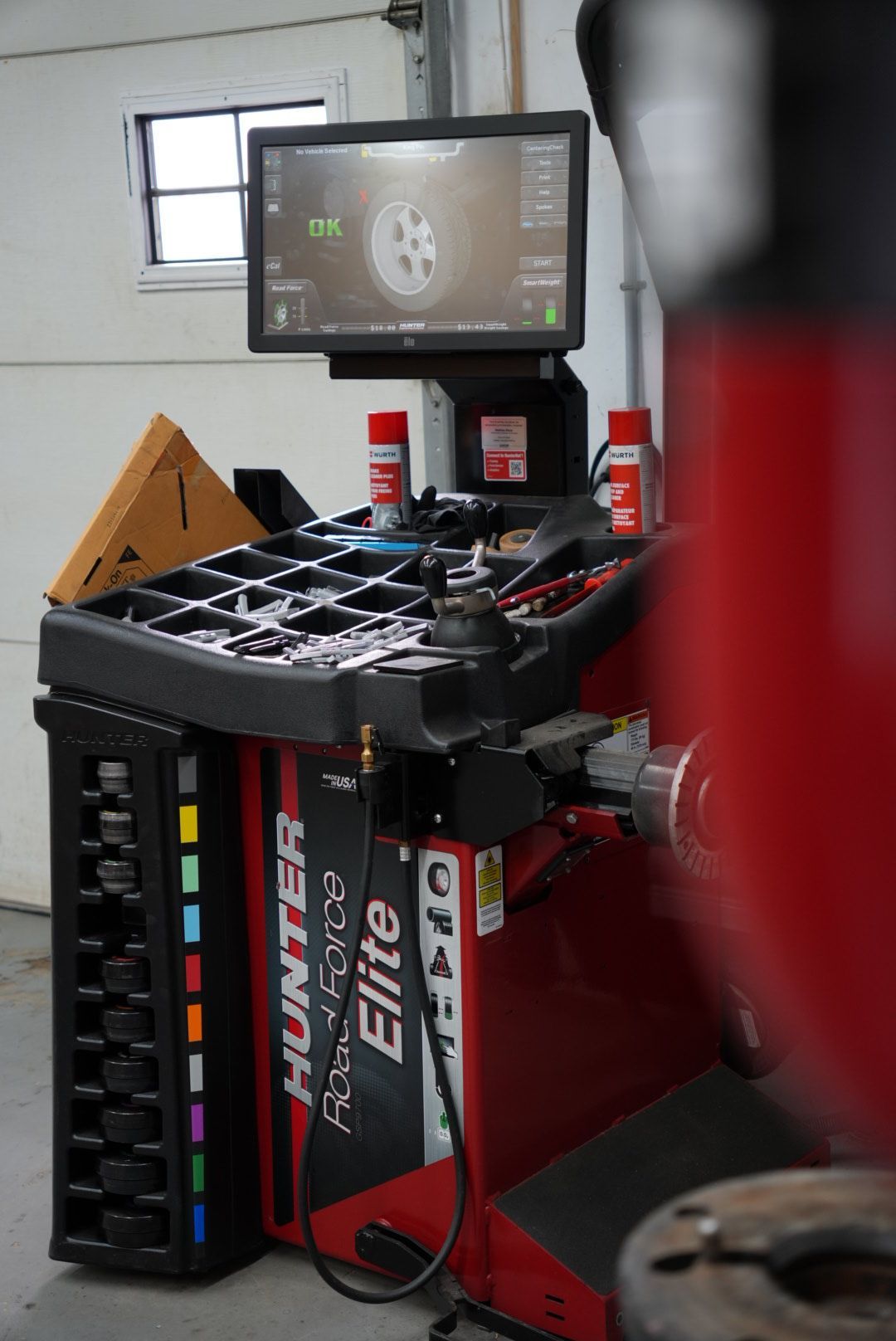 Une équilibreuse de roues Hunter Hawkeye Elite dans un garage, affichant les informations des roues sur un écran.