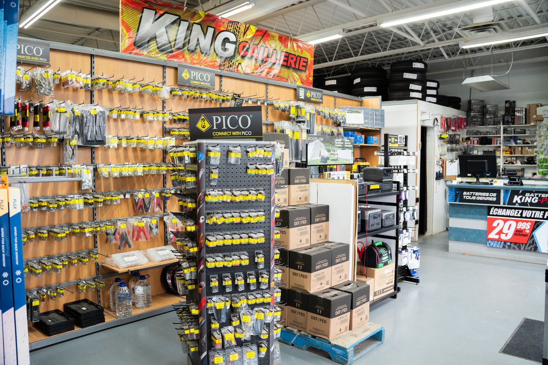 Intérieur d'un magasin présentant des articles de pêche et des pièces automobiles ; étagères remplies de produits, présentoirs.