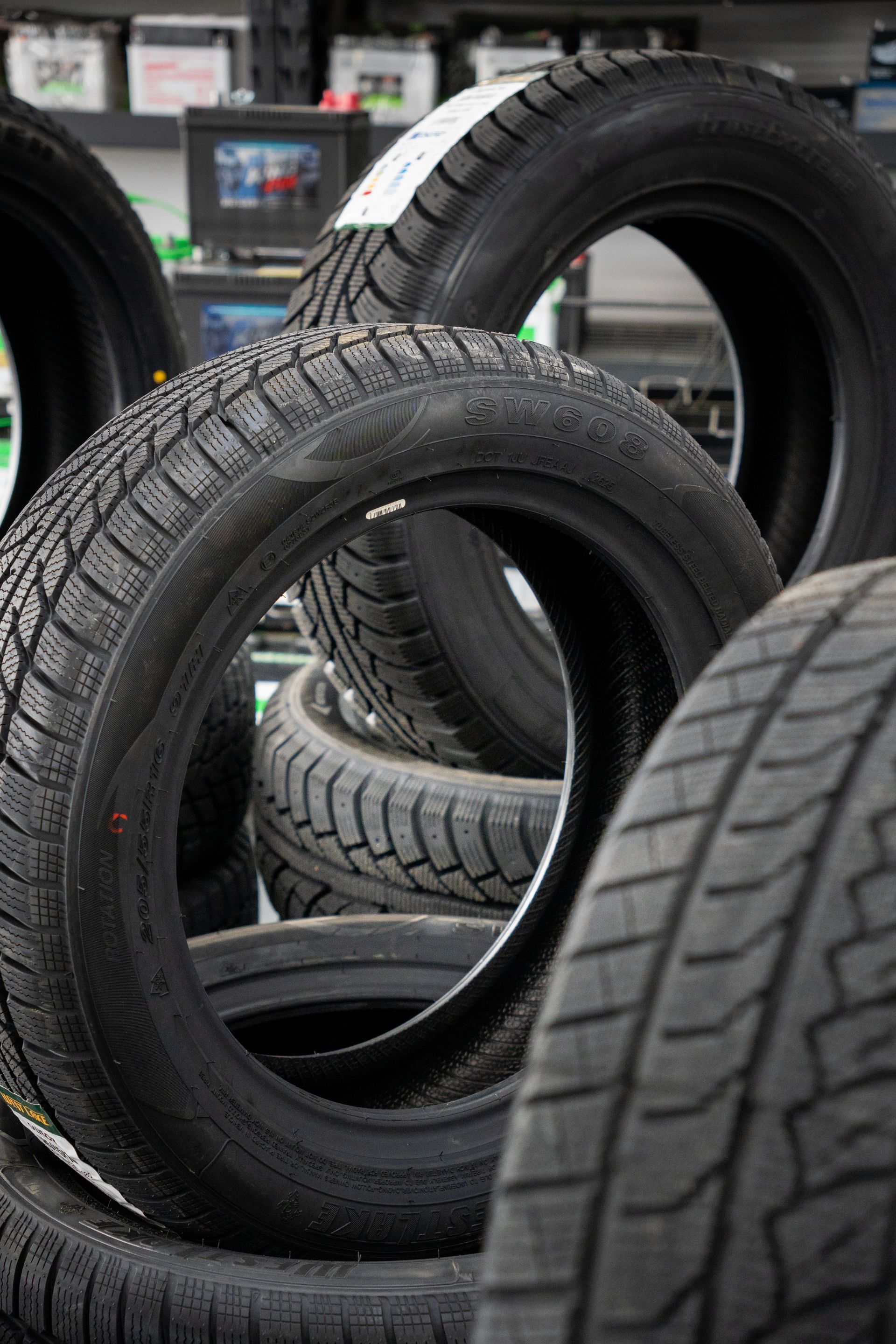 Des pneus empilés dans un atelier de pneumatiques, avec différents profils de bande de roulement visibles.