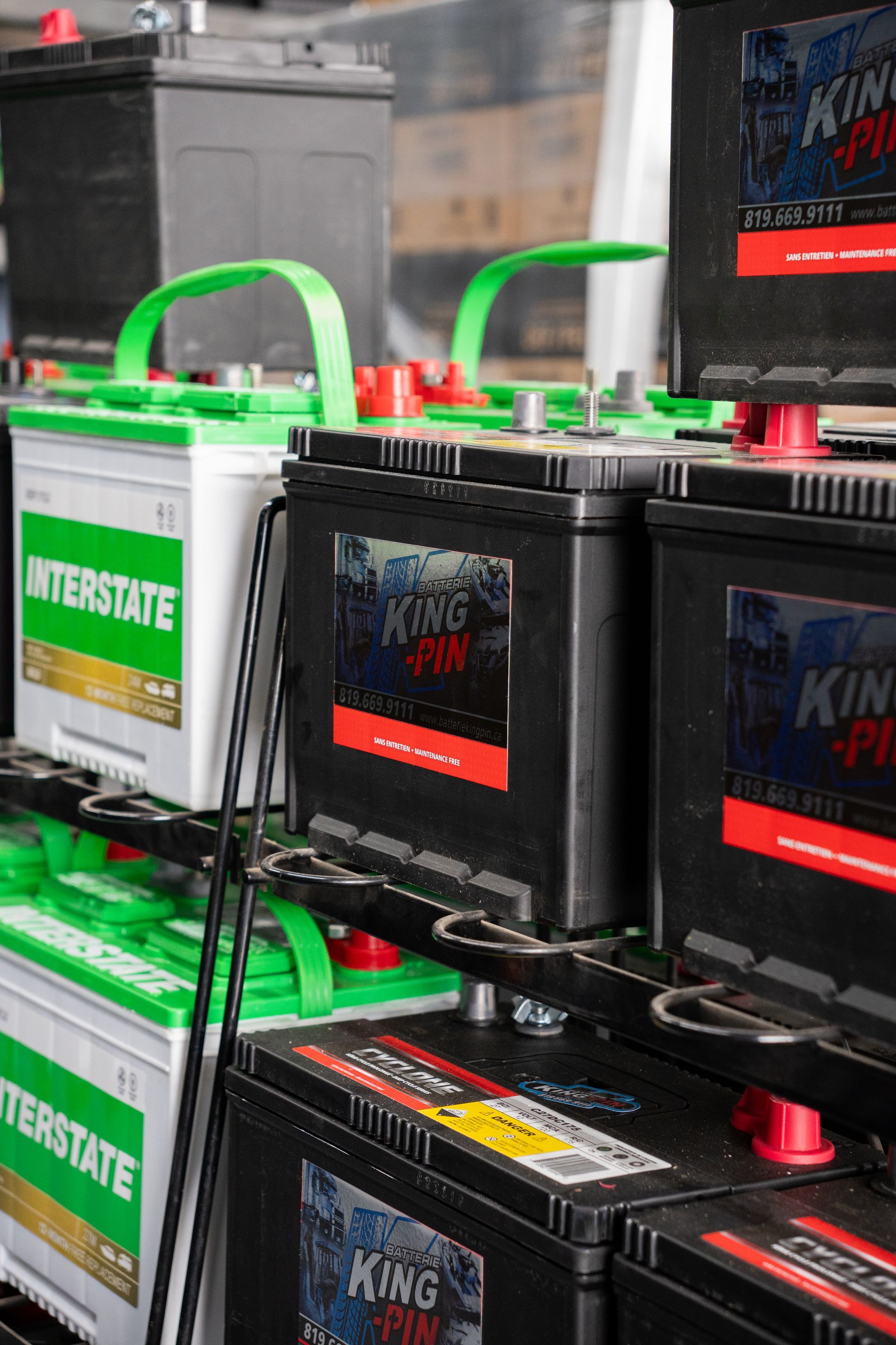 Des piles dans un magasin, certaines de marque « Interstate » et « King Pin », avec des touches de vert et de rouge.