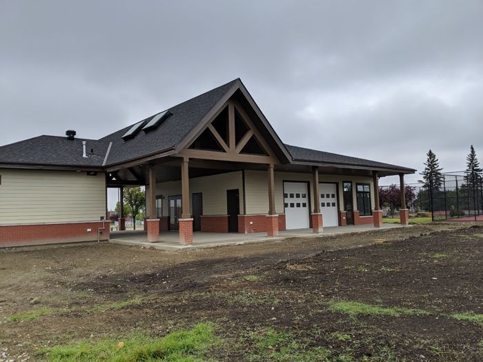 A light-colored building with a dark roof and large wooden supports on a cloudy day.
