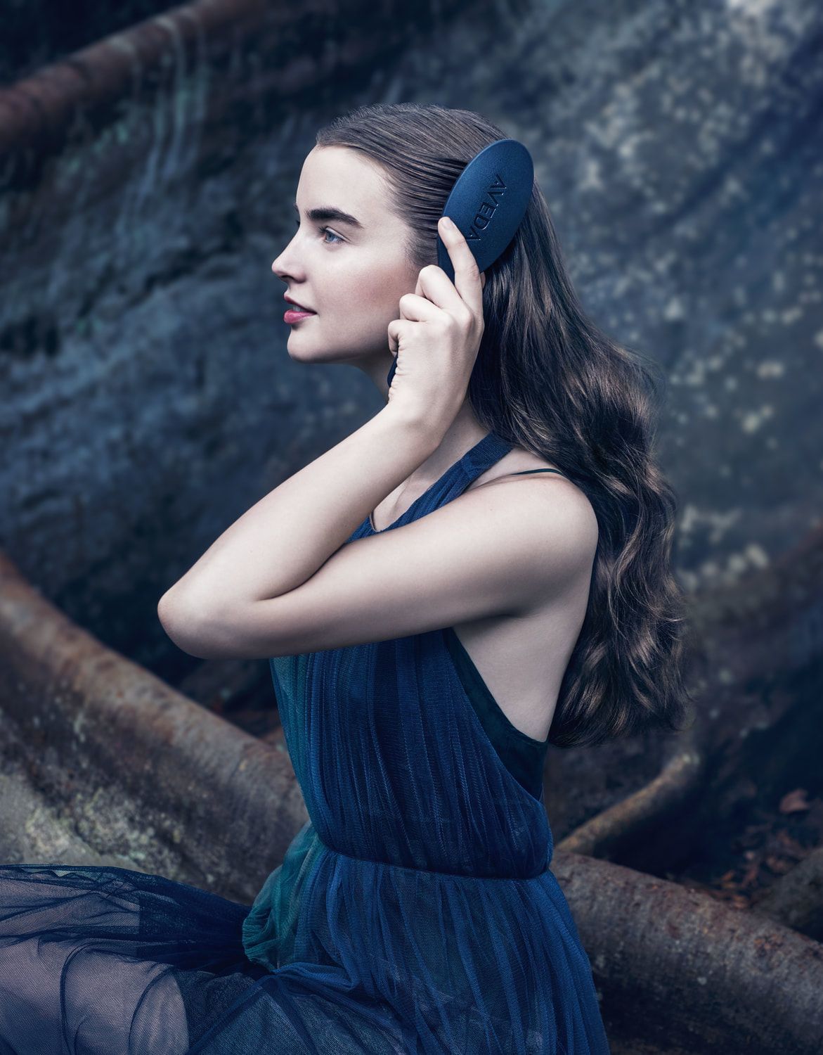A woman in a blue dress is brushing her hair