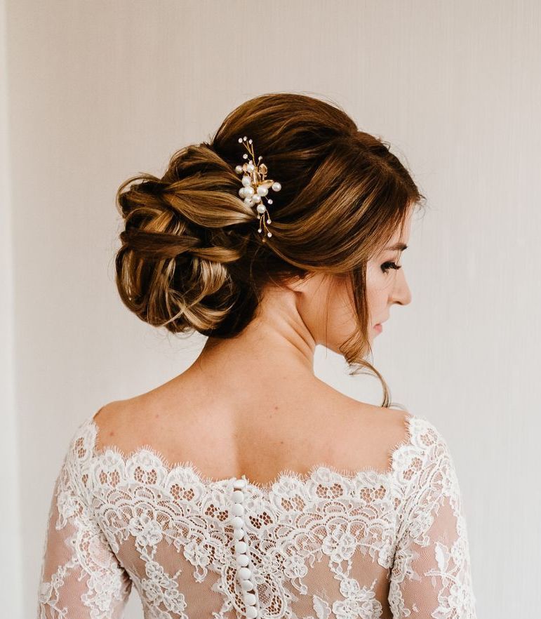 the back of a bride wearing a white lace wedding dress with her hair in a bun .
