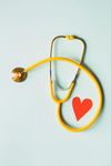 Yellow stethoscope and red heart on a light blue background, symbolizing healthcare.