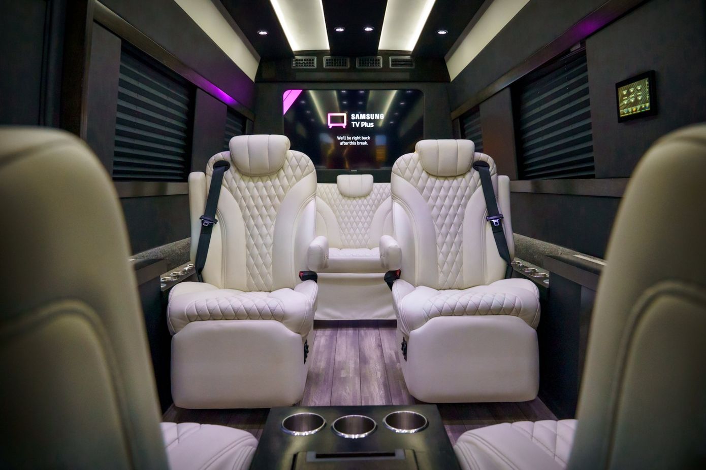 The inside of a van with white seats and a flat screen tv. executive coaches premium chauffeur service memphis  tn