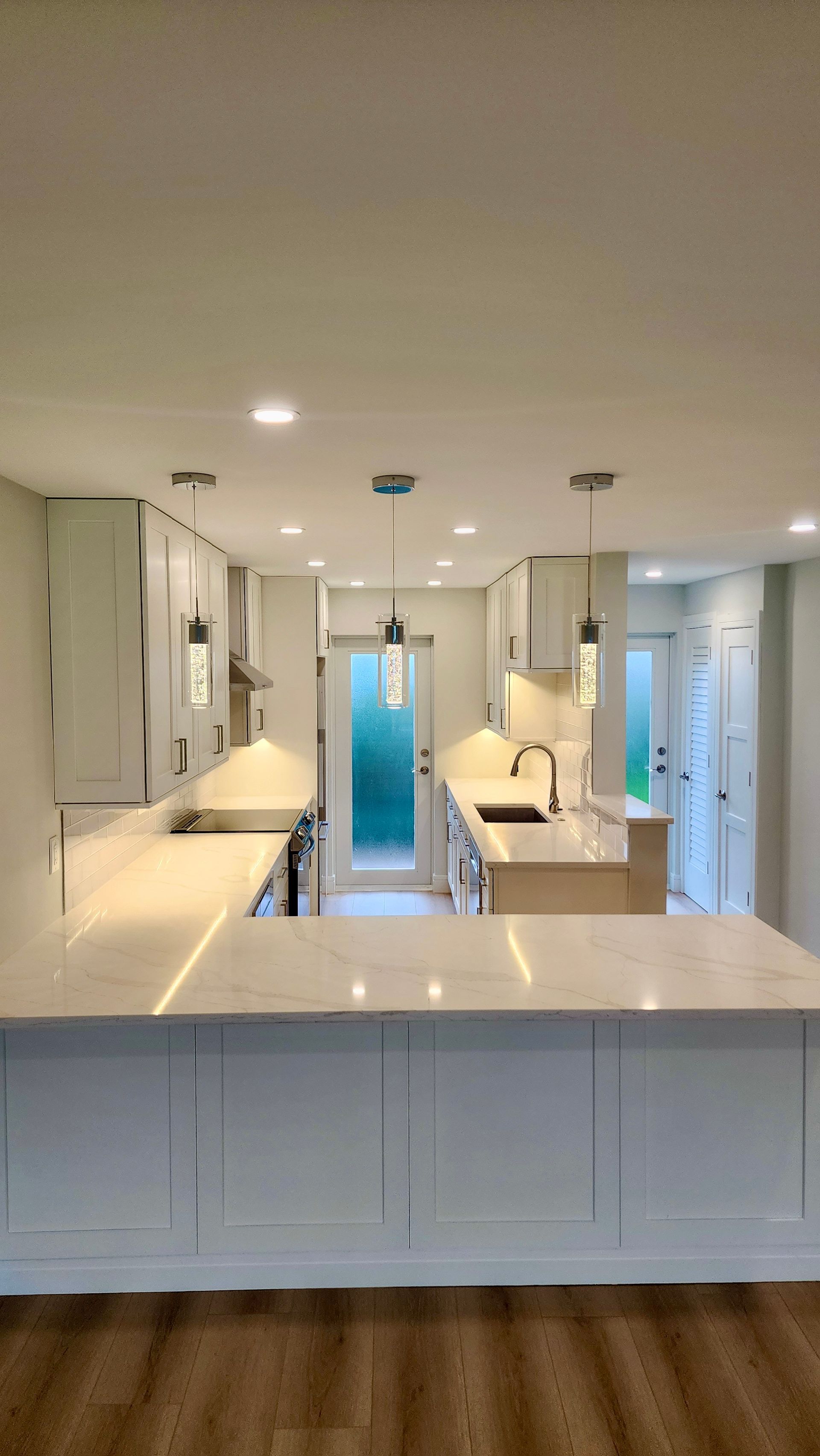 A kitchen with white cabinets , white counter tops , and a large island.