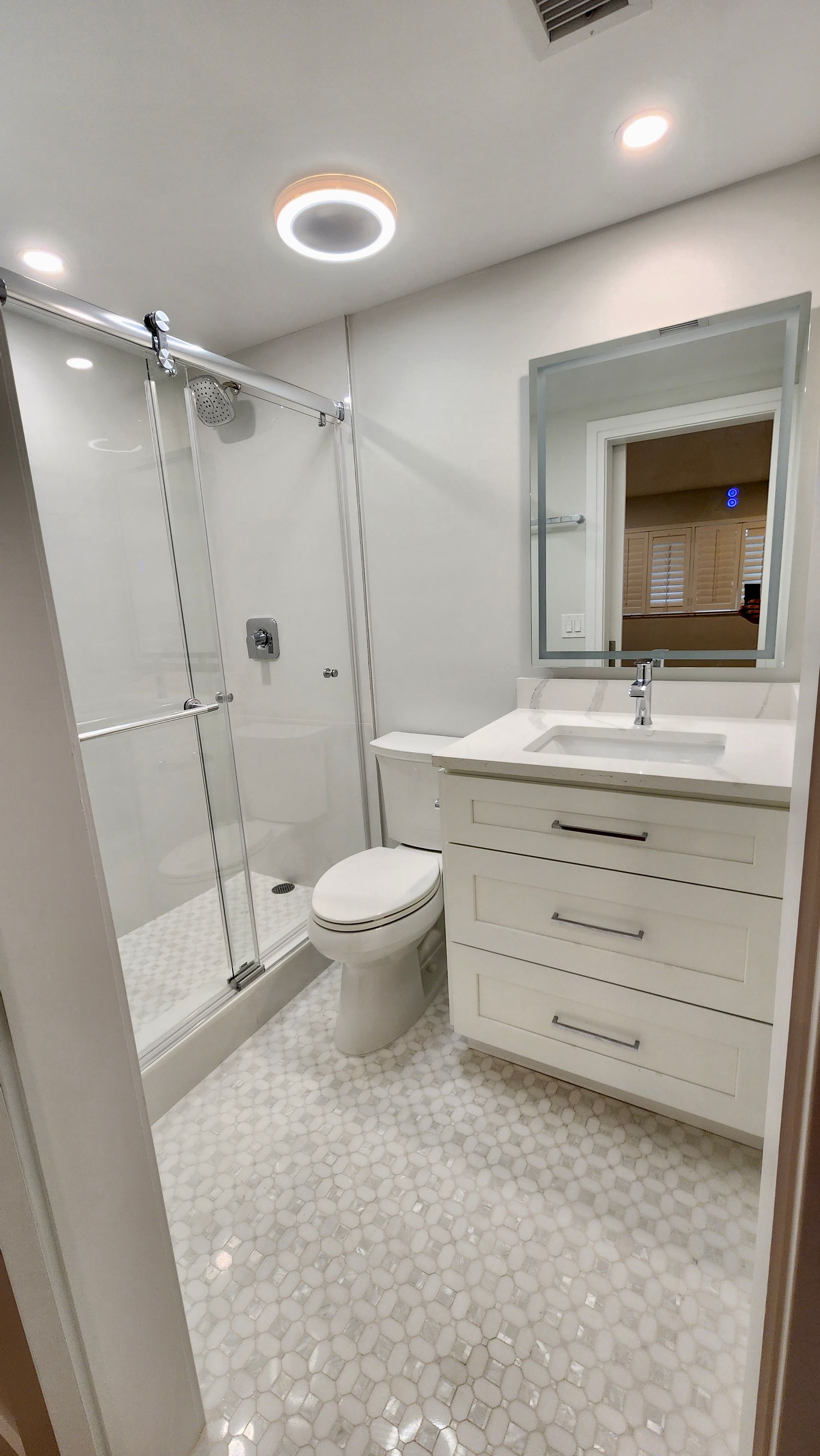 A bathroom with a toilet , sink , shower and mirror.