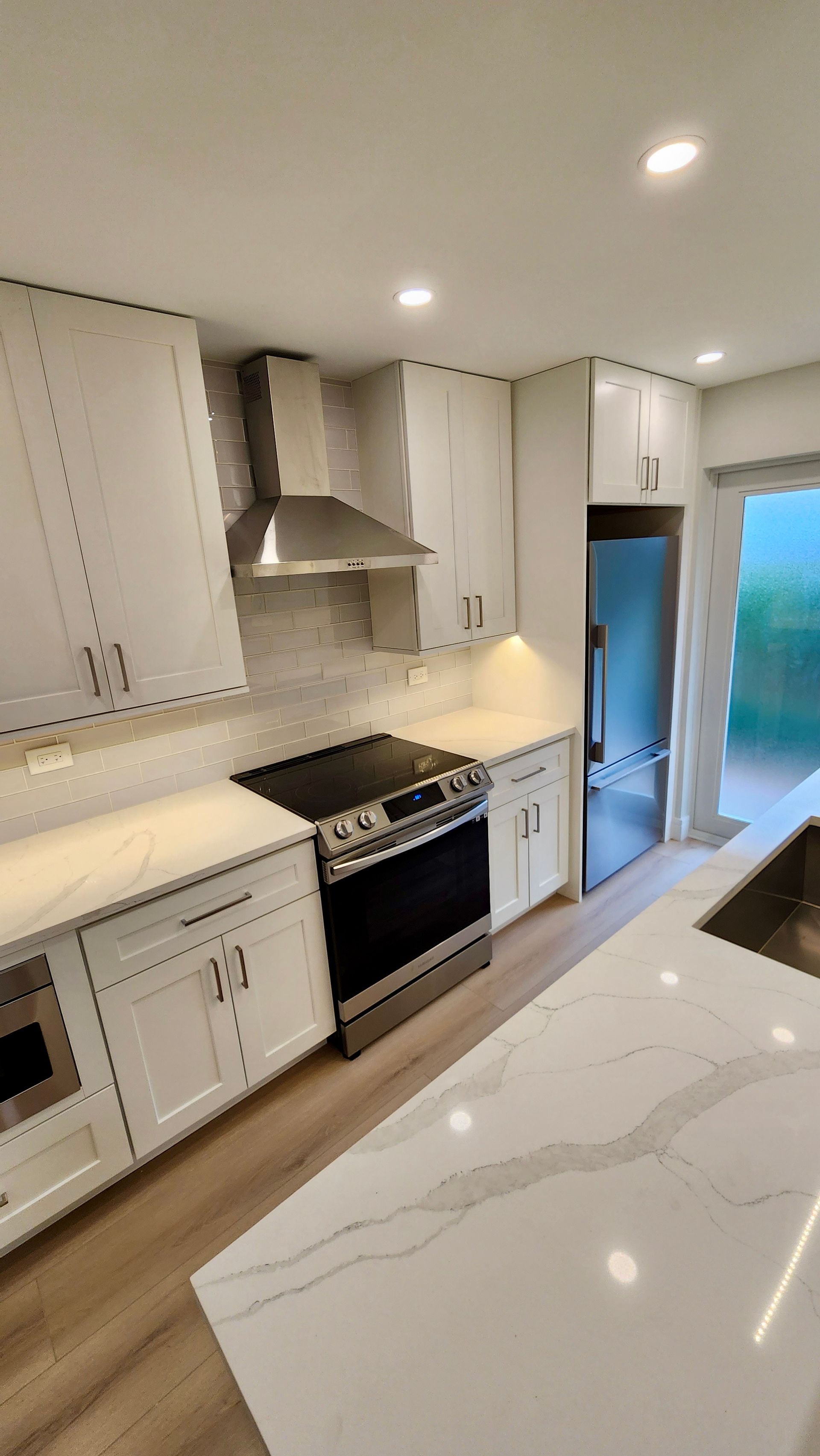 A kitchen with white cabinets , a stove , a refrigerator , and a sink.