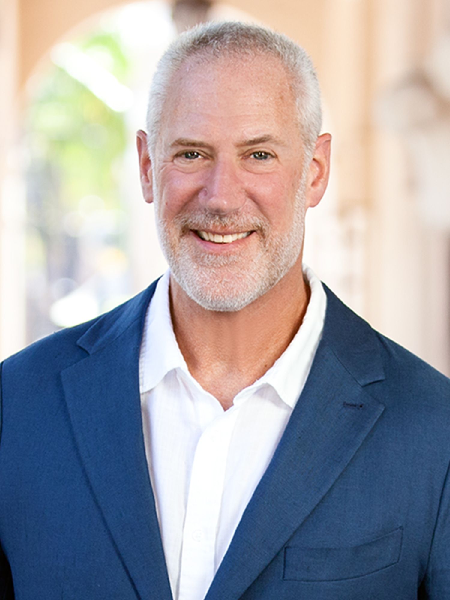 A man in a blue suit and white shirt is smiling for the camera.