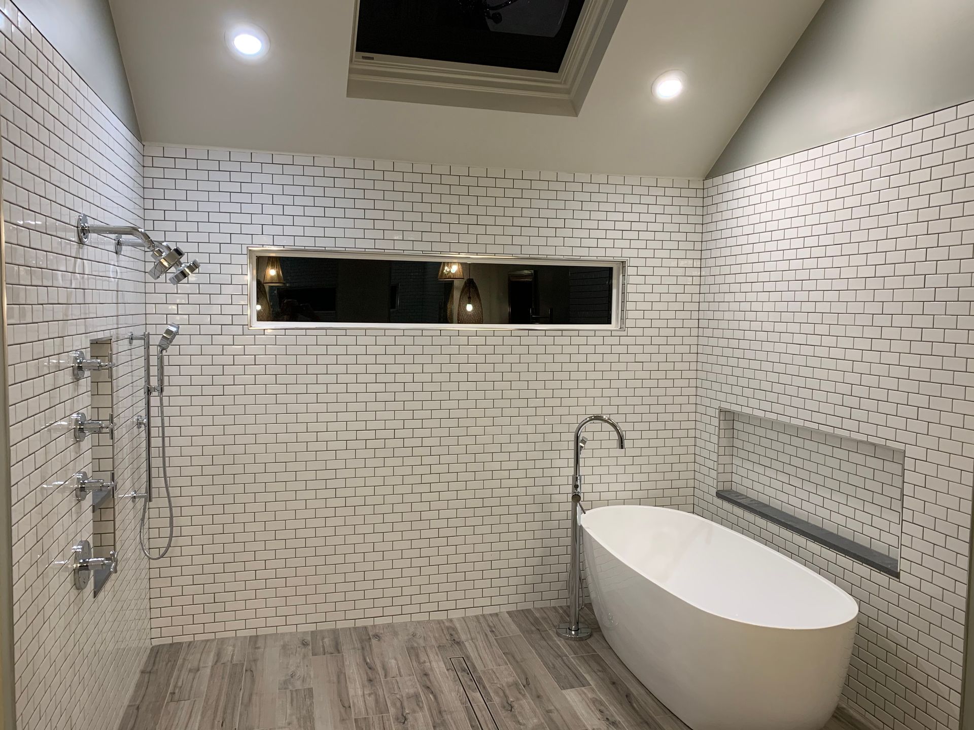A bathroom with a bathtub , shower , and skylight.