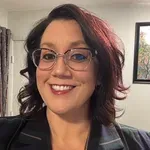 A man in a suit and tie stands in front of an american flag