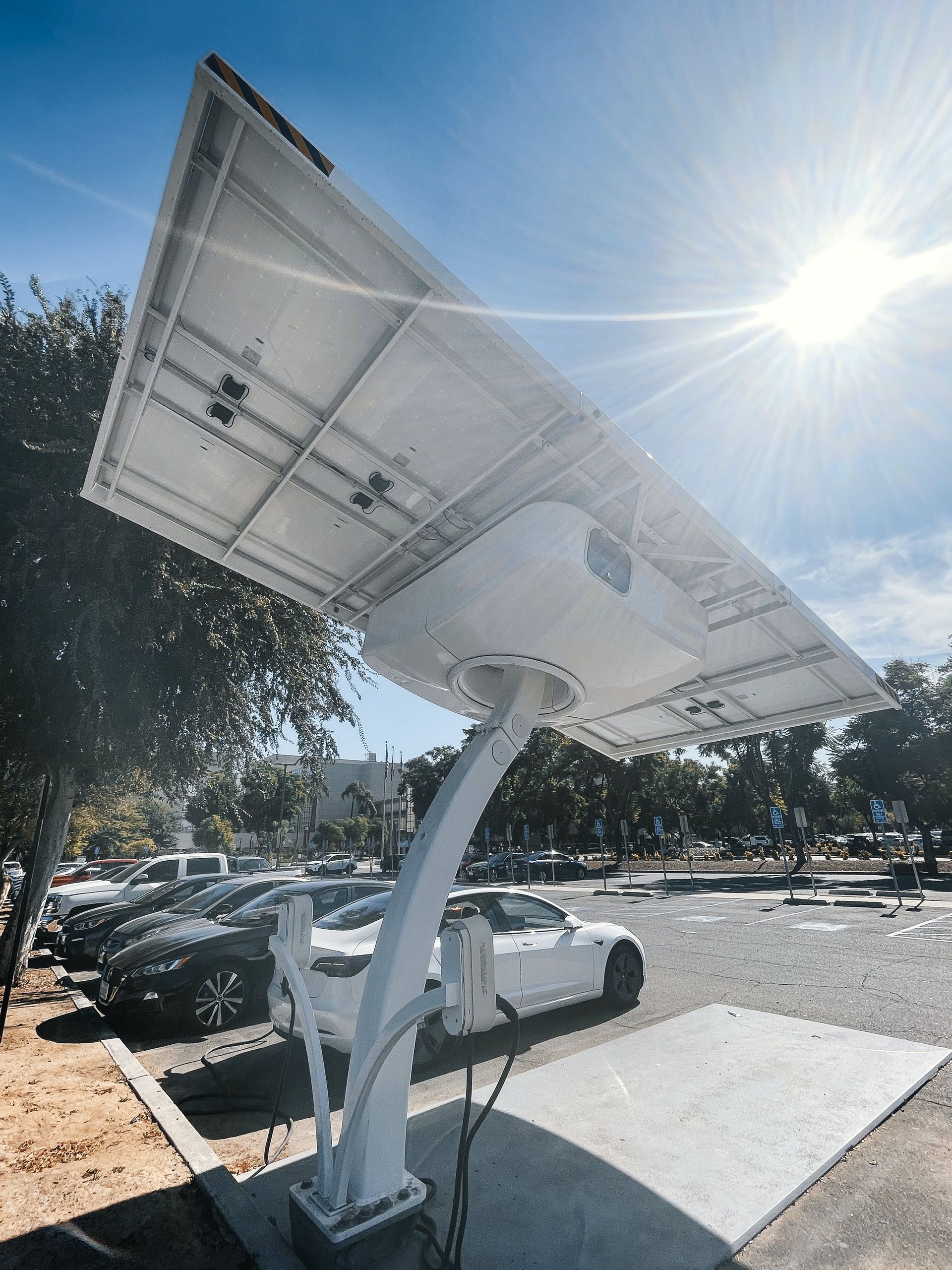 A white car is parked under a solar panel in a parking lot