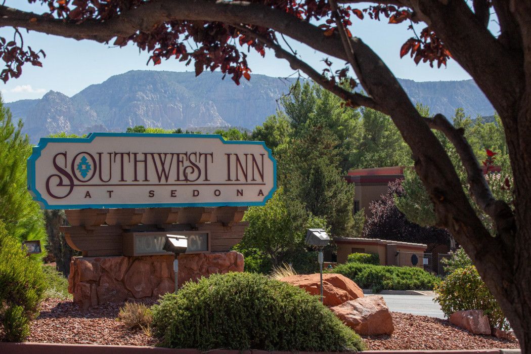 Southwest Inn Sedona sign placed under a tree, welcoming guests to the hotel