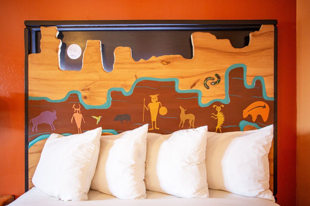 Hotel room at Southwest Inn Sedona with a bed featuring a wooden headboard and white pillows