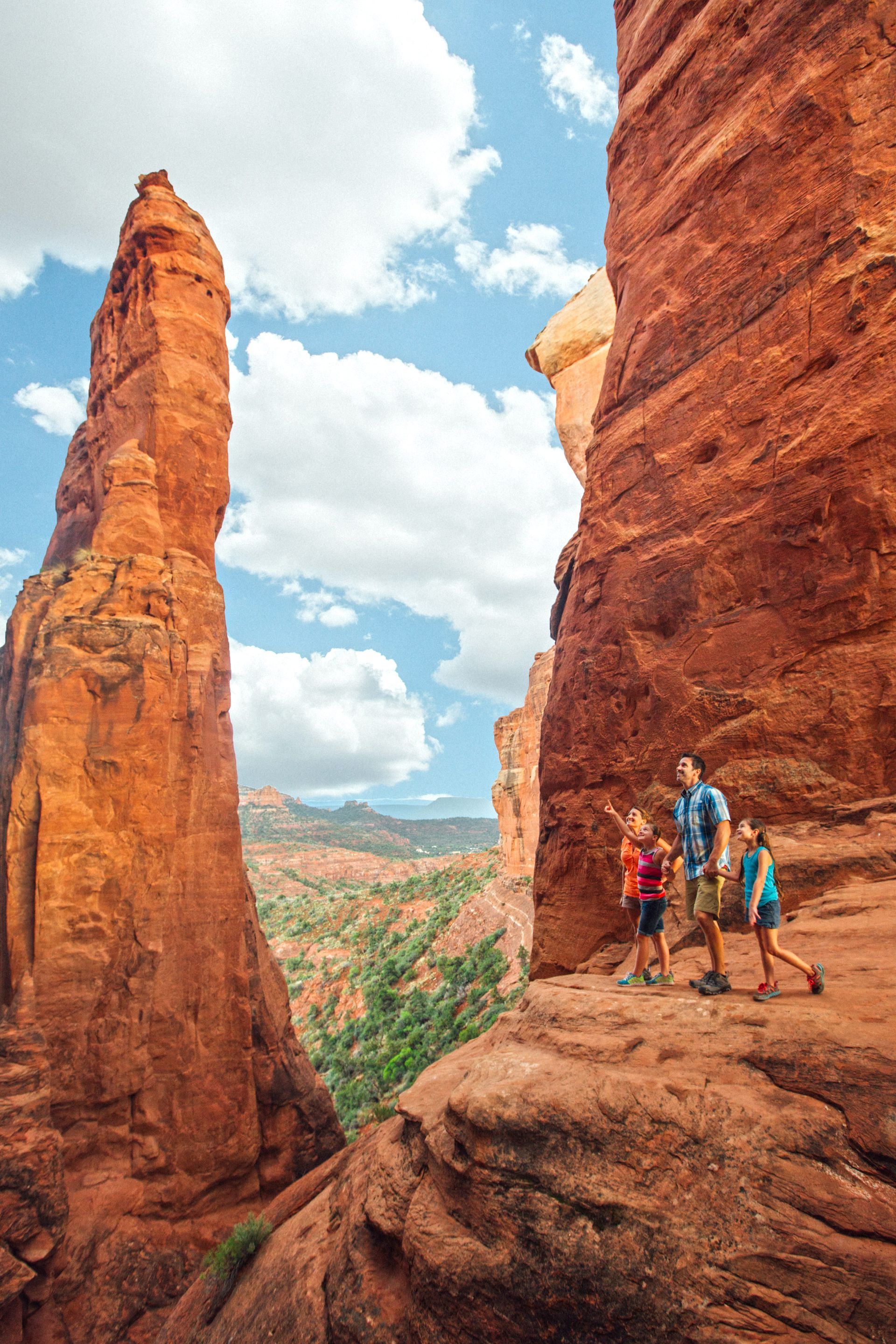 A group of people are standing on top of a rocky cliff.