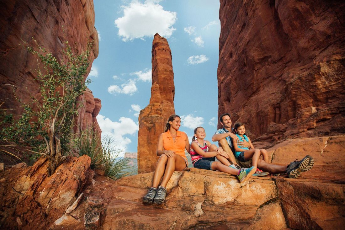 A family is sitting on a rock in the middle of a canyon.