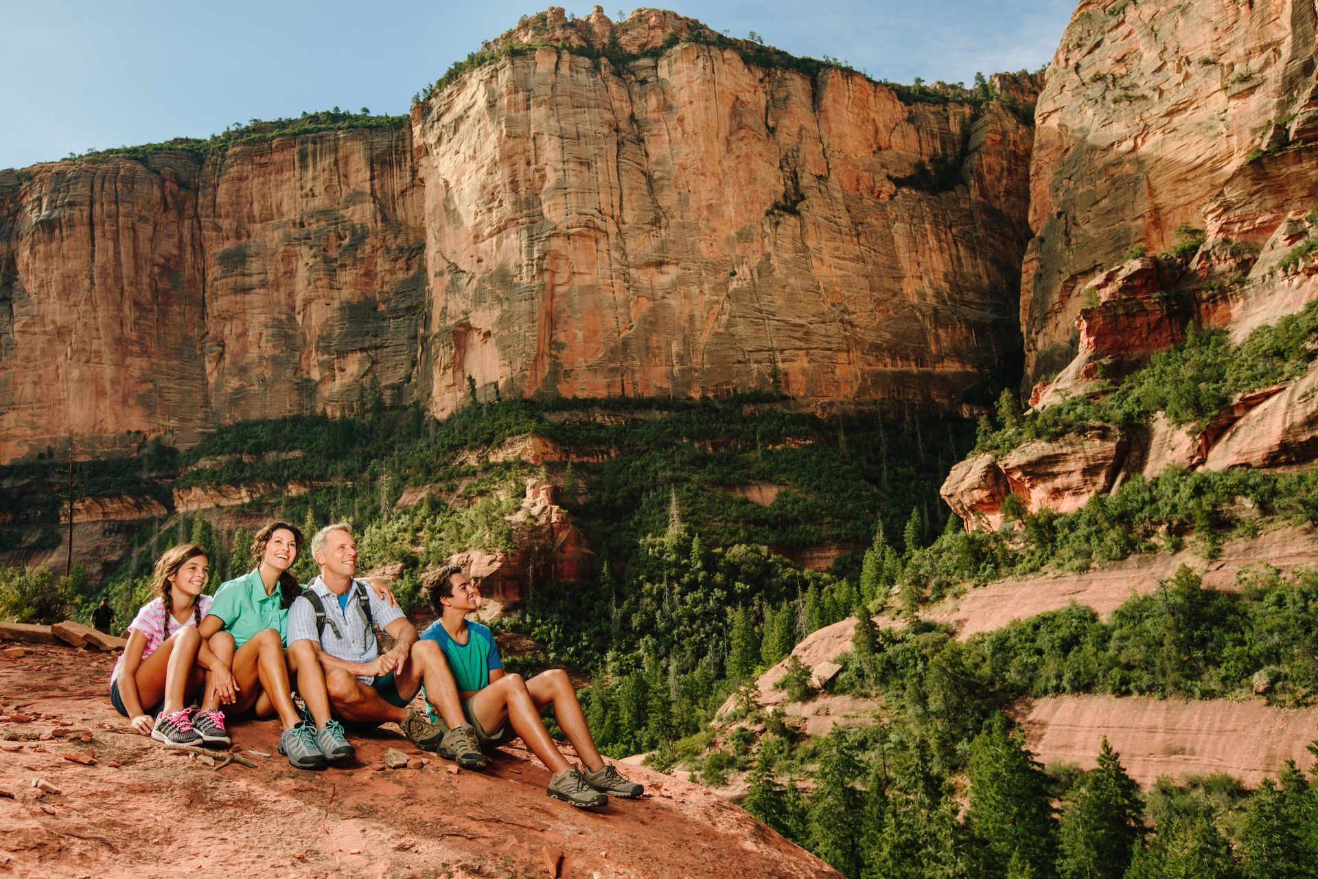 A group of people are sitting on the edge of a cliff.