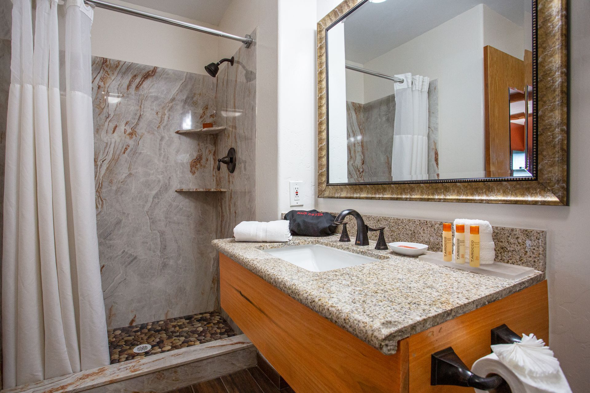 A bathroom with a sink , mirror and shower.