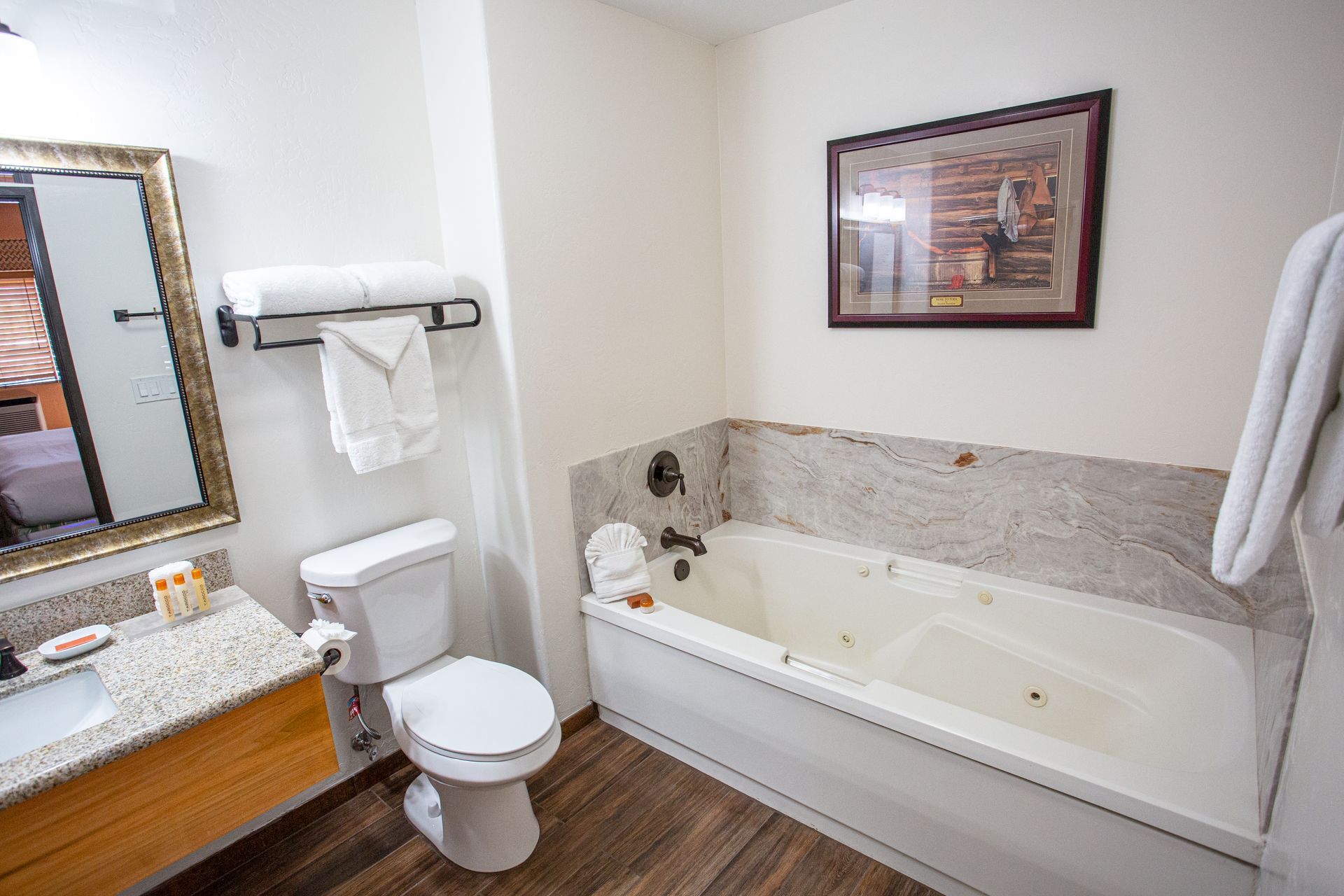 A bathroom with a jacuzzi tub , toilet , sink and mirror.