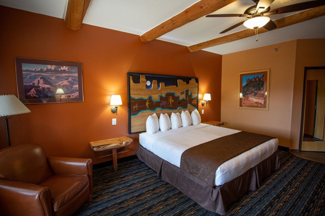 Hotel room at Southwest Inn Sedona with king-size bed, chair, table, and ceiling fan