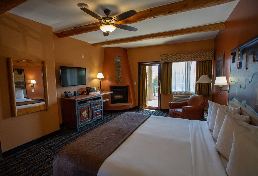 Hotel room at Southwest Inn Sedona with king-size bed, fireplace, flat-screen TV, and ceiling fan