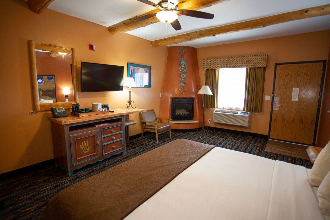 Cozy hotel room at Southwest Inn Sedona with king-size bed, fireplace, television, desk, and chairs