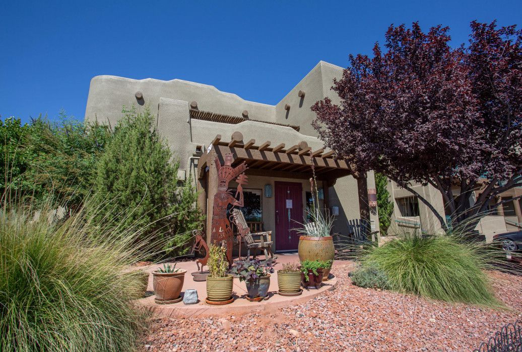 Large house with a red door surrounded by potted plants and trees near Southwest Inn Sedona