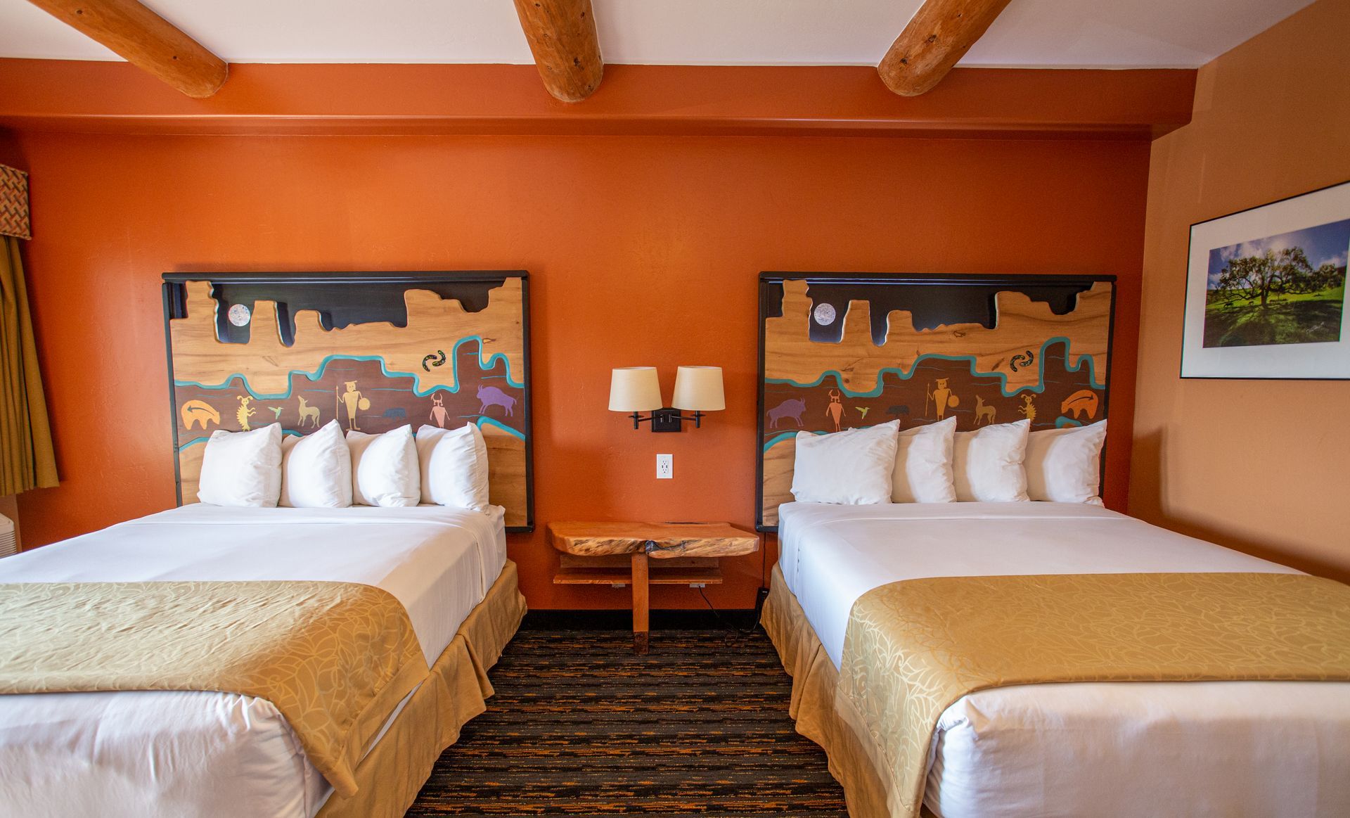 A hotel room with two beds and a picture on the wall.