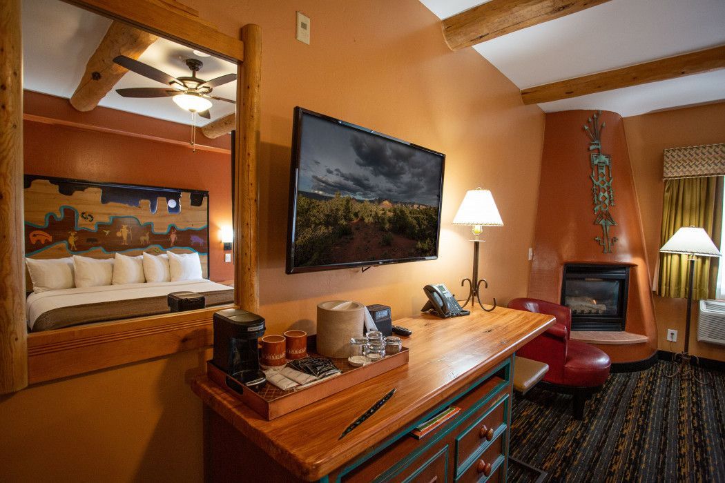 Hotel room at Southwest Inn Sedona with bed, work desk, flat-screen television, and cozy fireplace