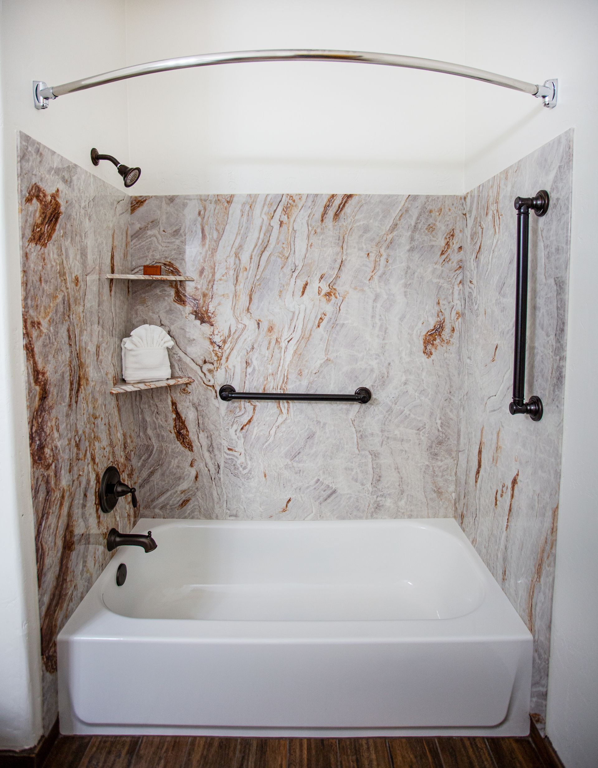 A bathroom with a bathtub and a shower with marble walls.